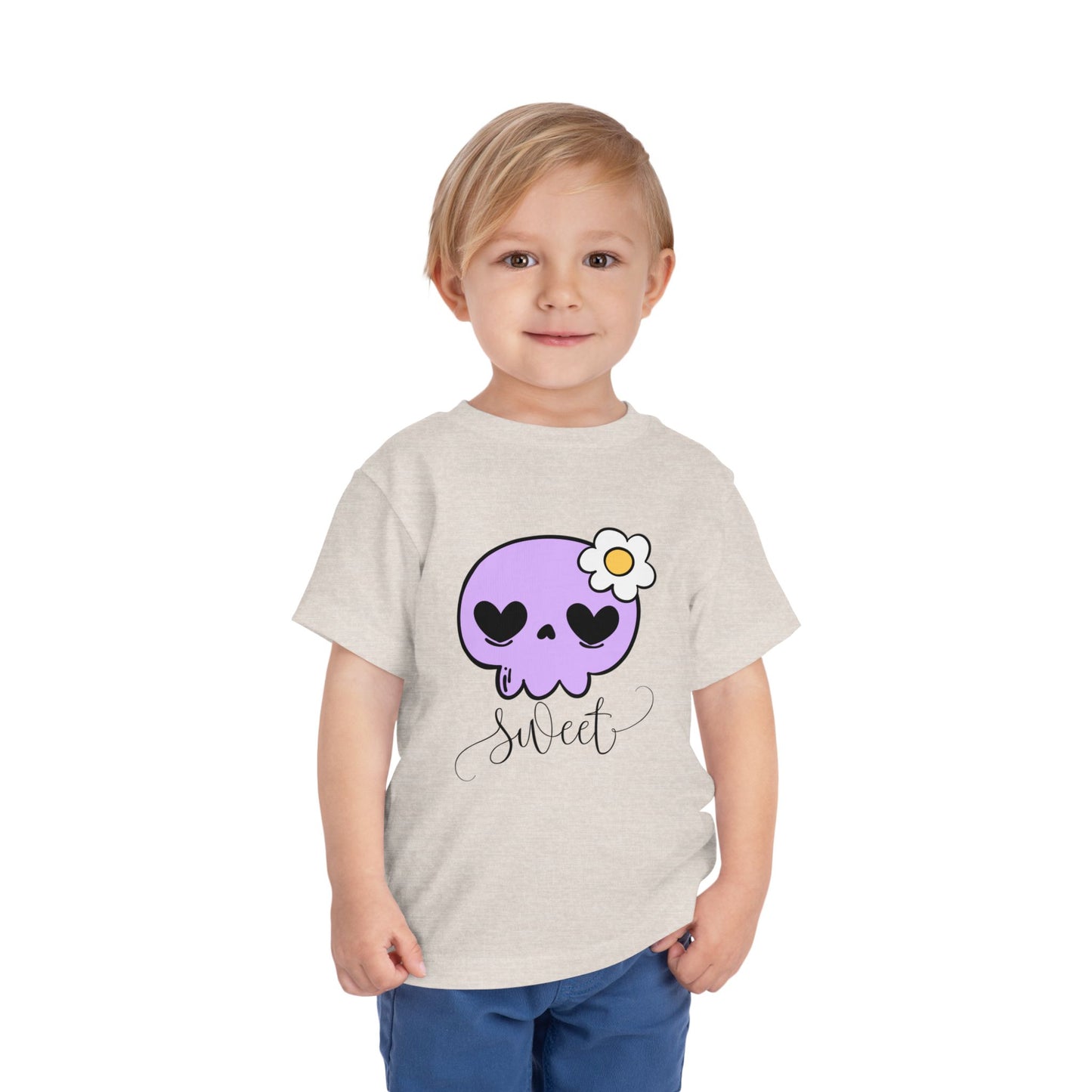 Child wearing a tan toddler t-shirt with a purple skull design and the word 'sweet' 