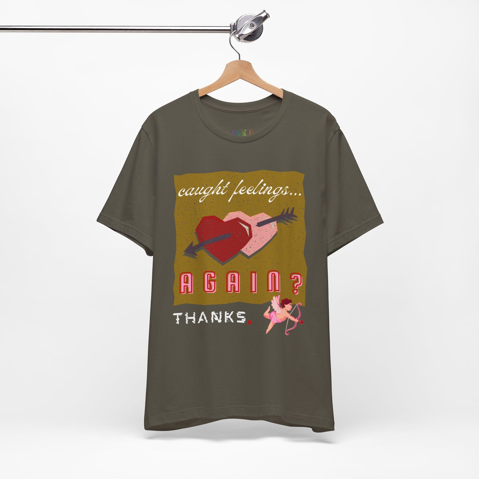 Military green t-shirt with double heart graphic design and text 'Caught Feelings AGAIN? Thanks,' followed by a picture of cupid