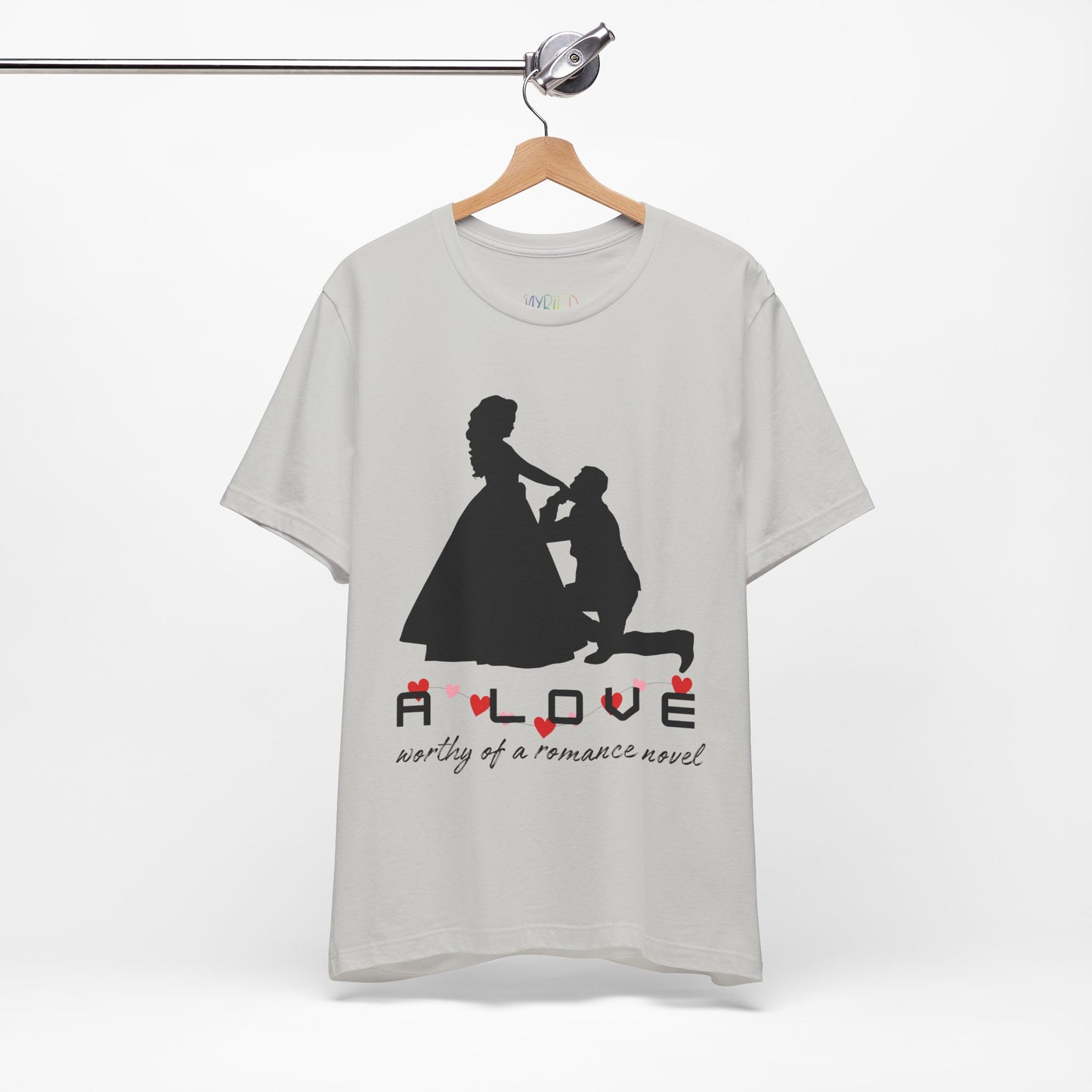 Silver t-shirt with black graphic if a man kneeling in front of a woman in a gown and text 'A LOVE worthy of a romance novel'