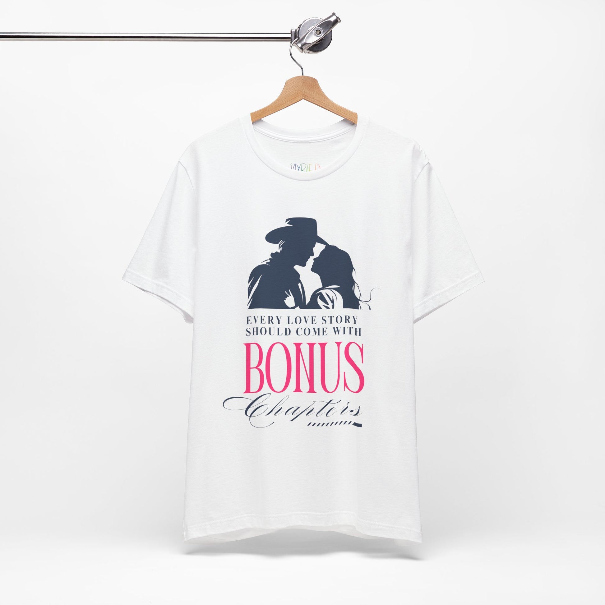 White t-shirt with western graphic of a man and woman leaning in for a kiss, text "Every Love Story Should Come With BONUS Chapters'