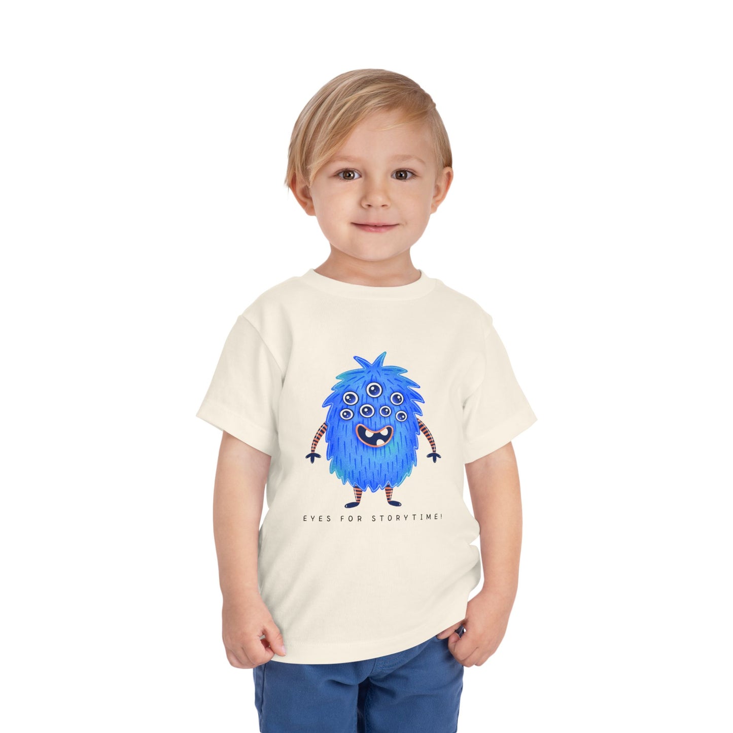 Child wearing a beige toddler t-shirt with a blue multi-eyed cartoon monster and text 'eyes for storytime!'