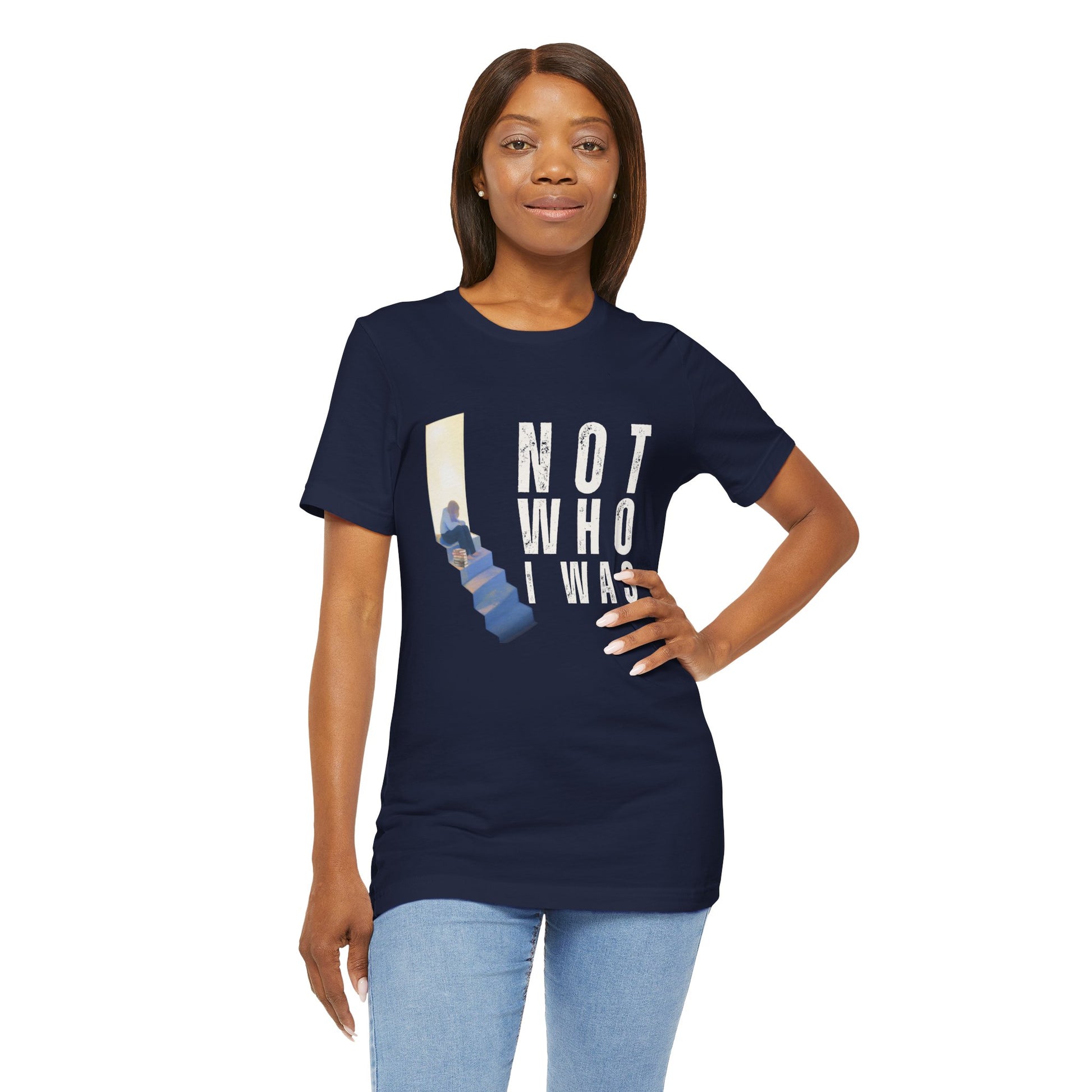 Woman wearing a navy blue t-shirt with person sitting at the top of the stairs, lit from behind and text 'Not Who I Was'