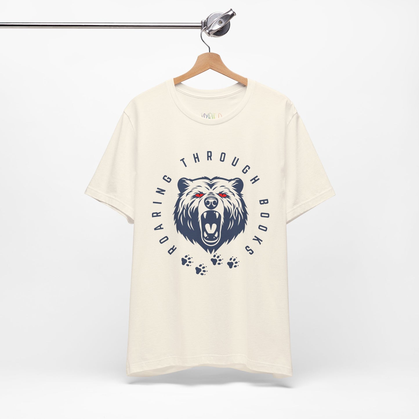 Beige t-shirt with a navy bear graphic, red eyes and circular text 'Roaring Through Books'