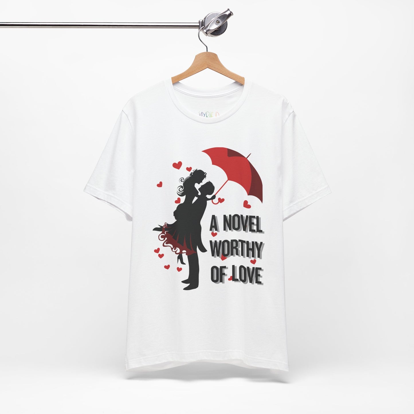 White t-shirt with a black graphic design of a man holding a woman under a red umbrella, sprinkled with hearts and text 'A Novel Worthy of Love' 