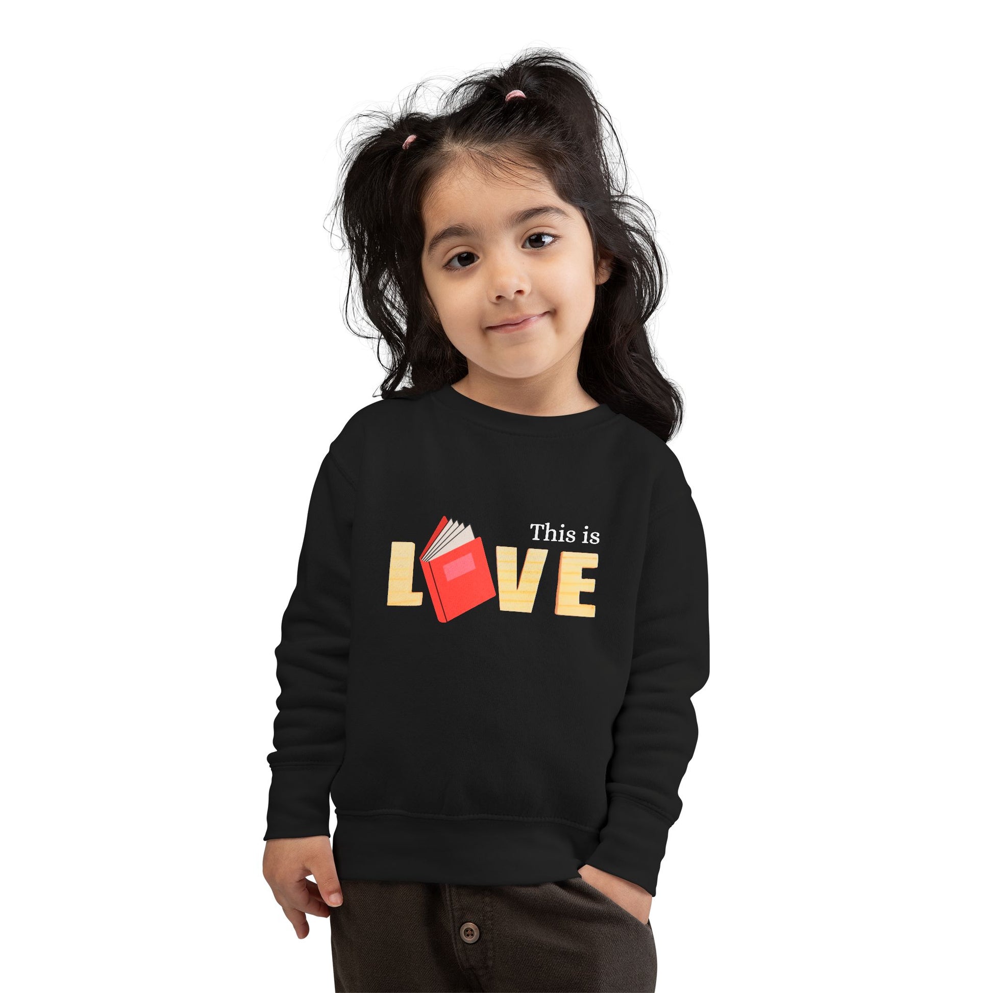 Girl wearing a black toddler 'This is Love' sweatshirt featuring a book in place of the letter O