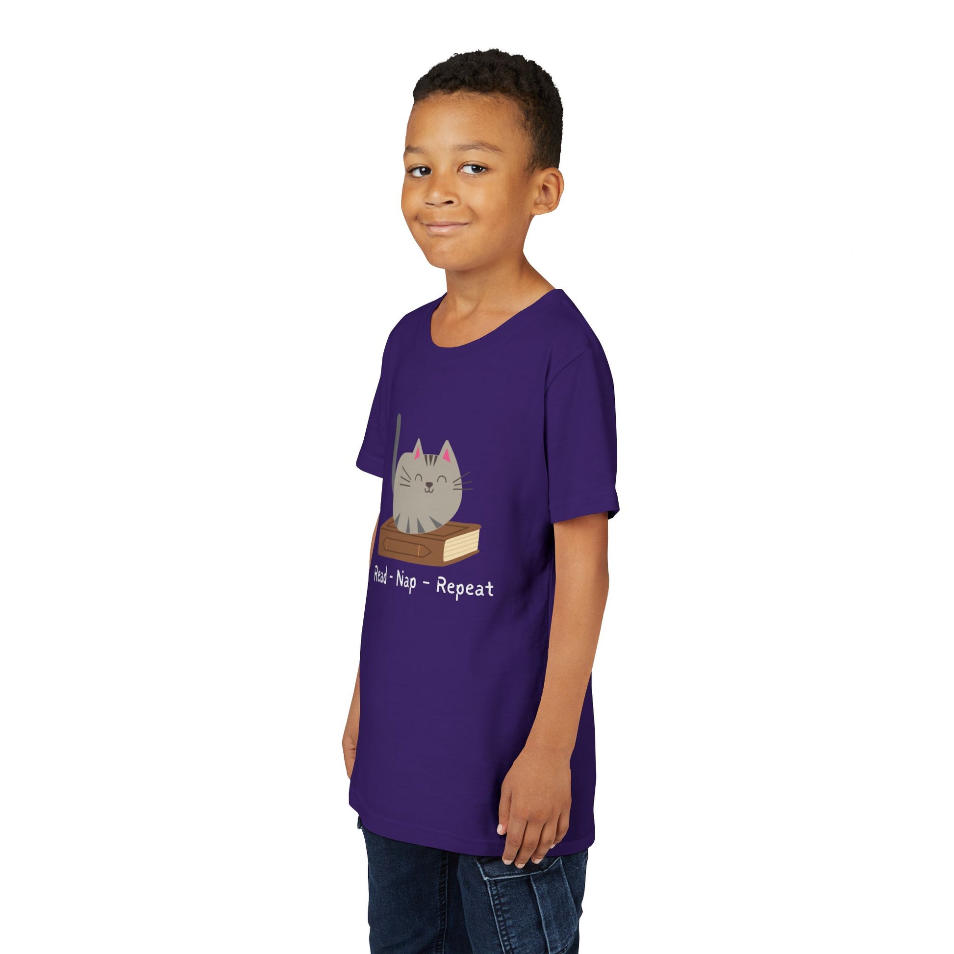 Boy wearing a purple t-shirt with a cat sitting on a book and text 'Read - Nap - Repeat' 