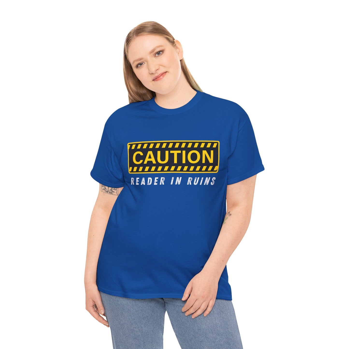 Woman wearing a blue t-shirt with yellow and black 'Caution' graphic and text beneath ' Reader In Ruins'