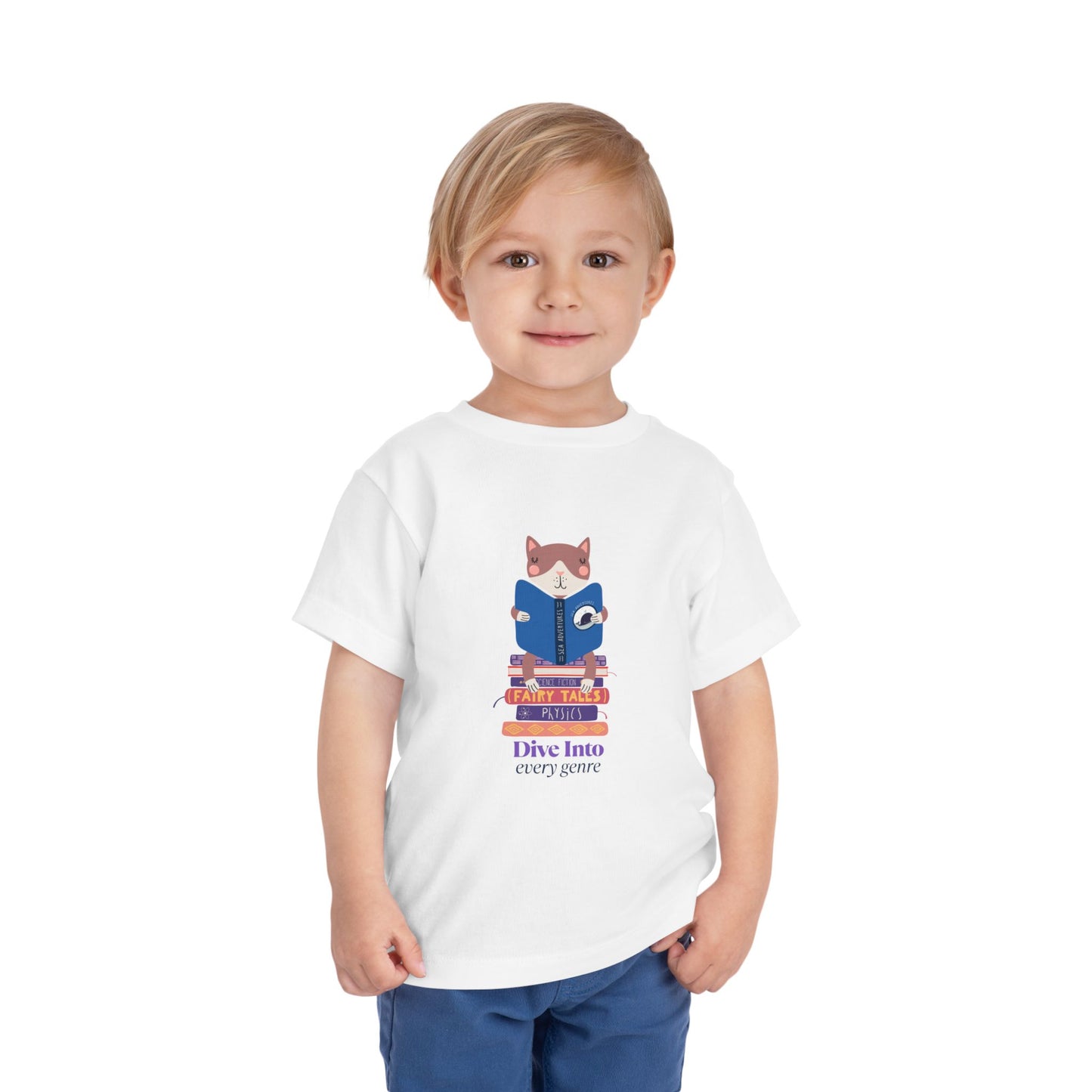 Child wearing a white toddler t-shirt with a cat reading a book while sitting on a stack of books and text 'Dive Into Every Genre'
