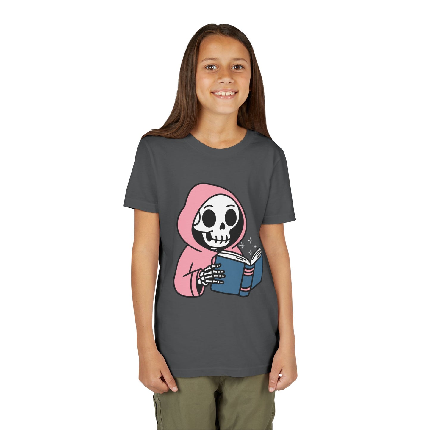 Girl wearing a gray t-shirt with a cartoon skeleton wearing a pink hoodie and reading a book