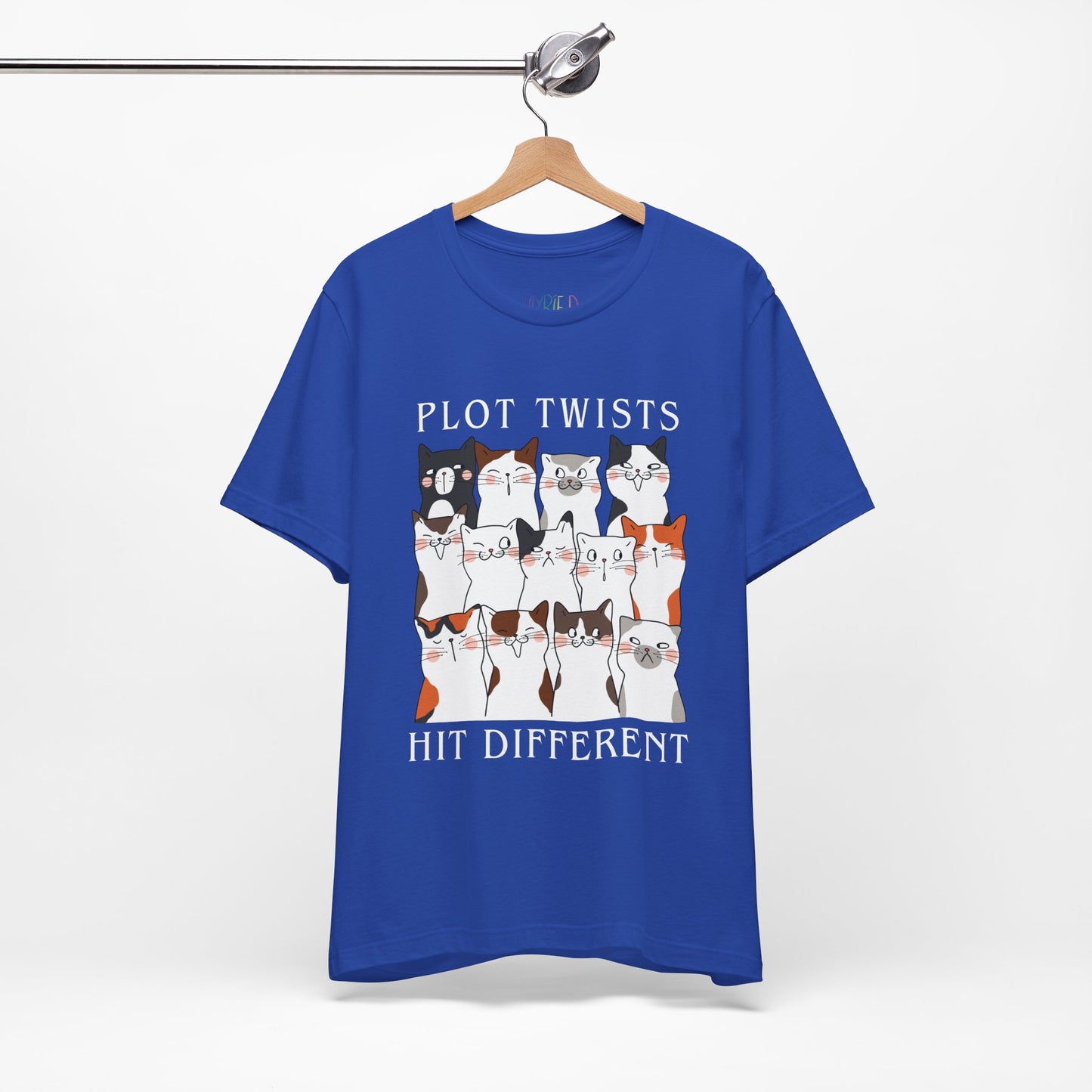 Blue t-shirt with rows of cats making different faces and text 'Plot Twists Hit Different' 