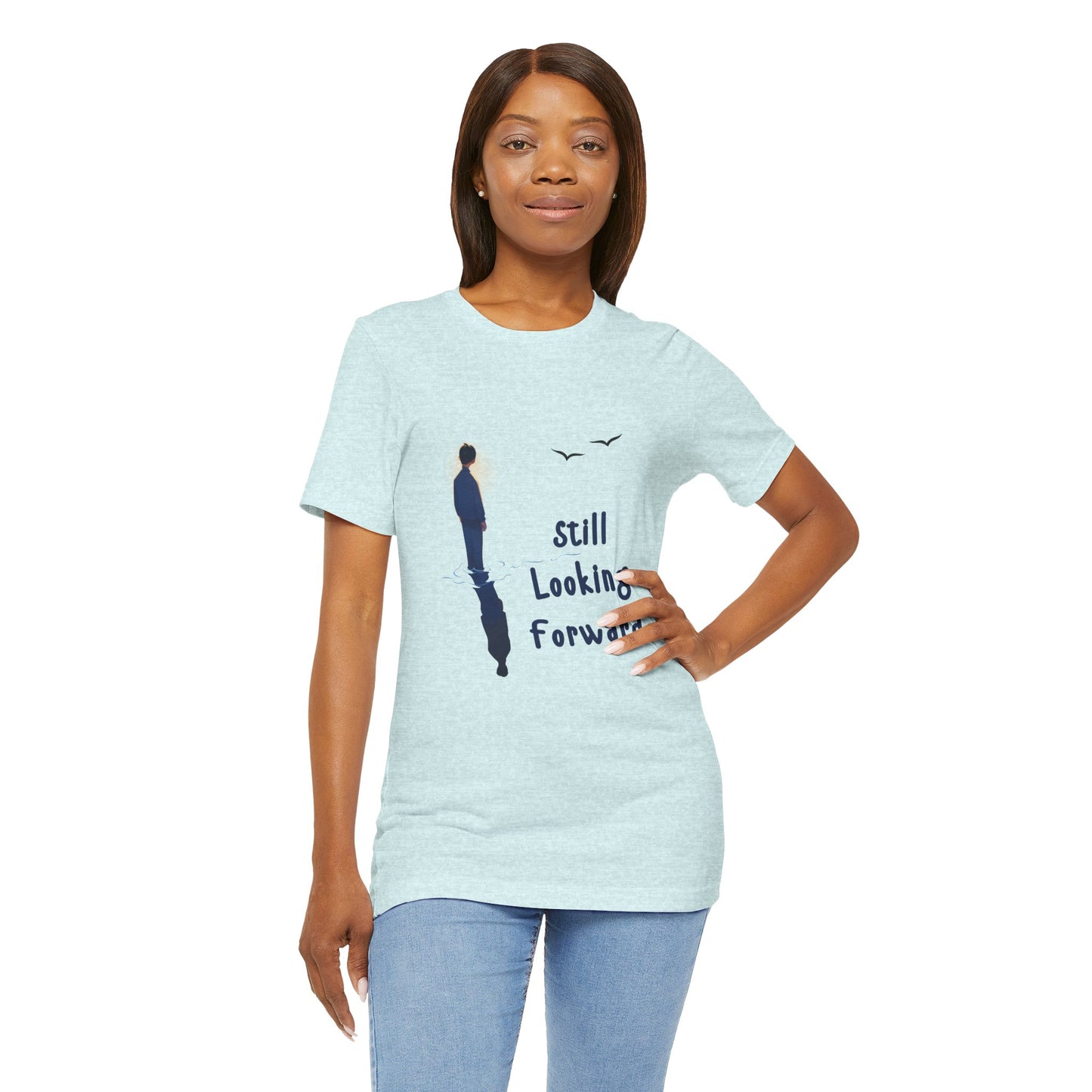 Woman wearing an ice blue t-shirt with graphic of a person standing in the water with his reflection and text 'Still Looking Forward' 