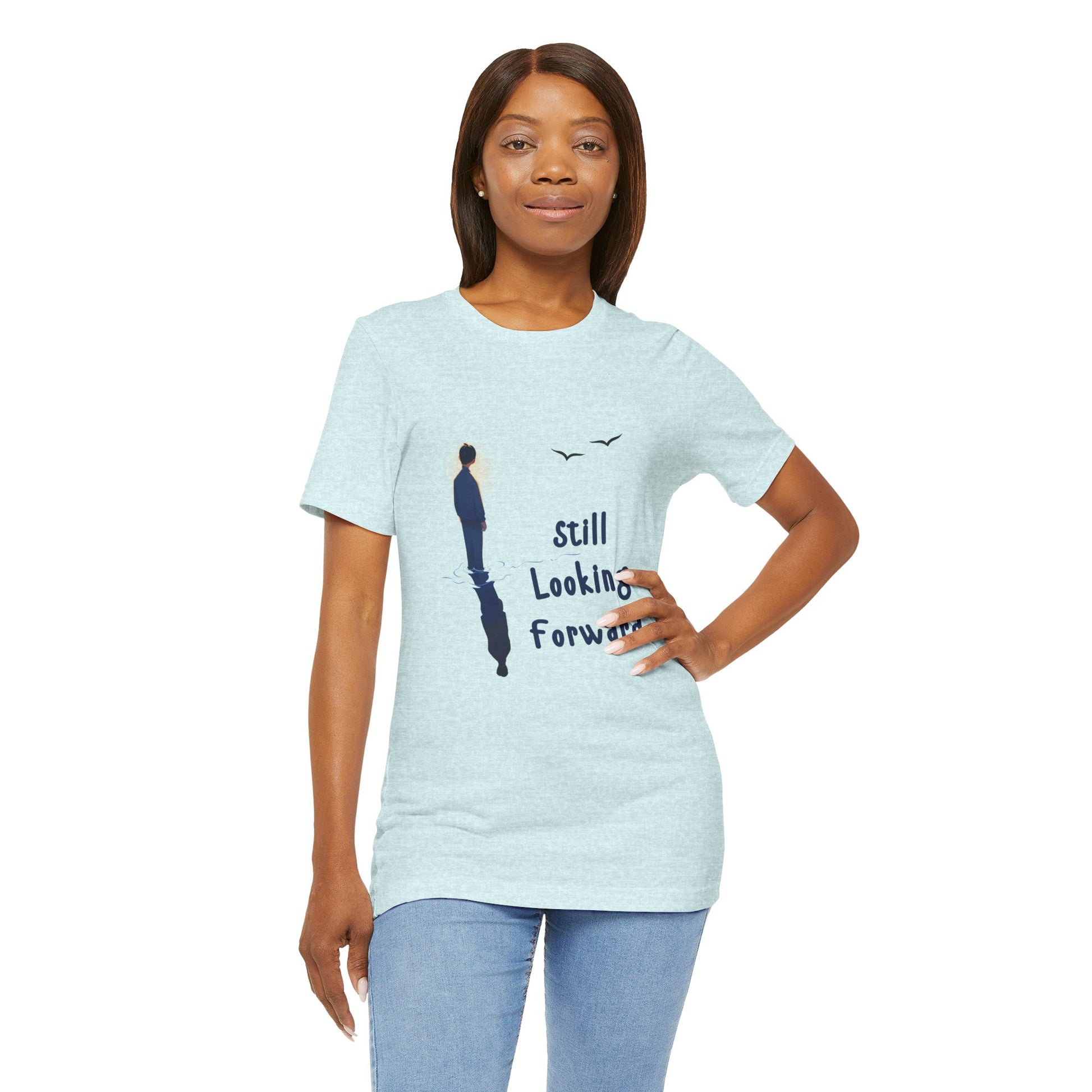 Woman wearing an ice blue t-shirt with graphic of a person standing in the water with his reflection and text 'Still Looking Forward' 