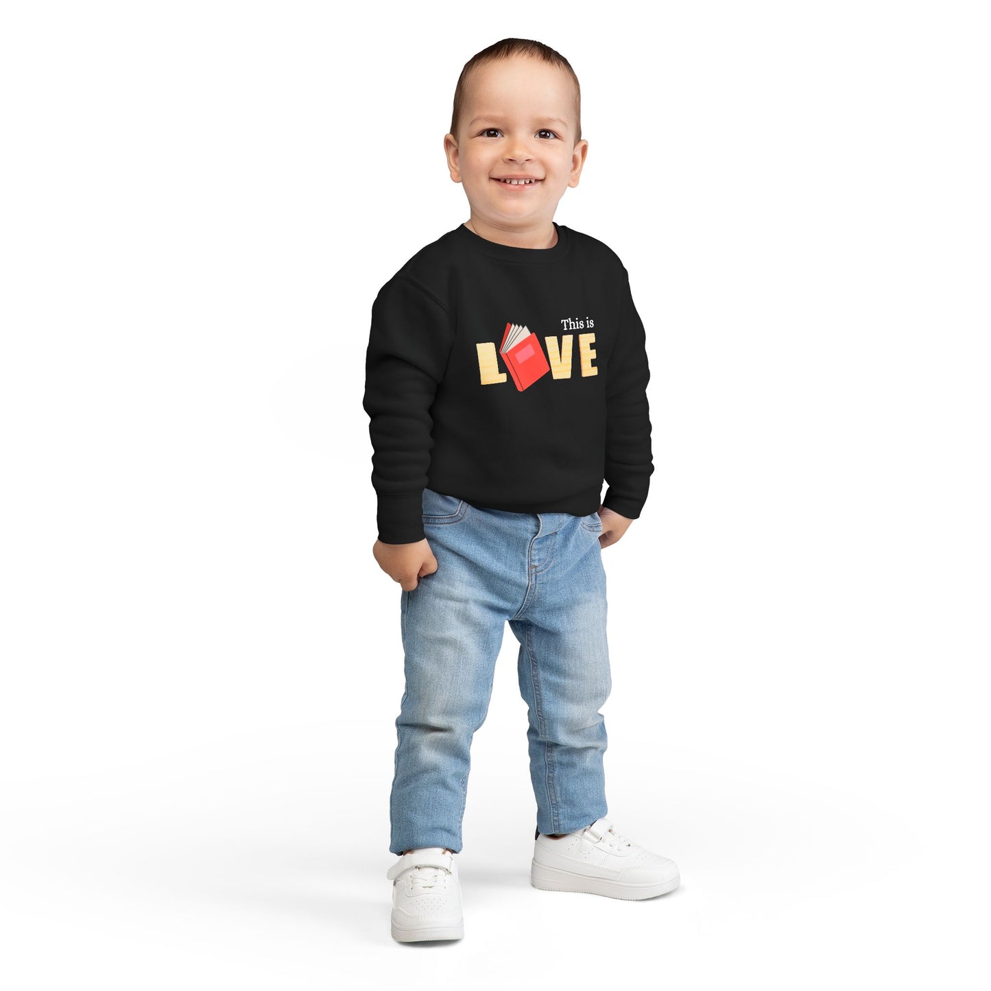 Boy wearing a black toddler 'This is Love' sweatshirt featuring a book in place of the letter O