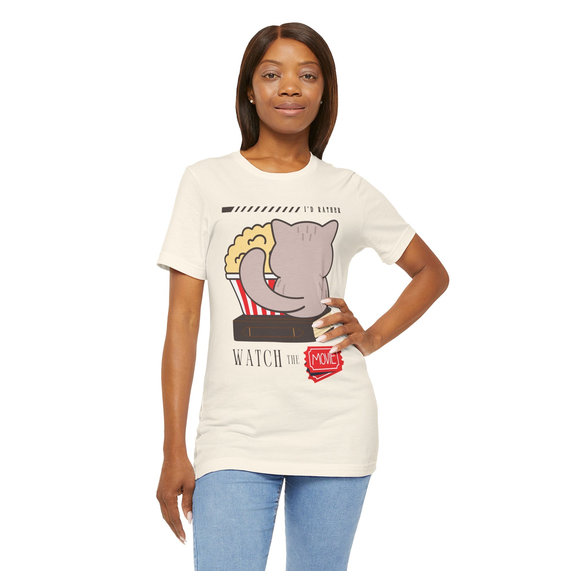 Woman wearing a beige t-shirt with the back of a cat, sitting on a book, with a bucket of popcorn, and text 'I'd Rather Watch The Movie' 