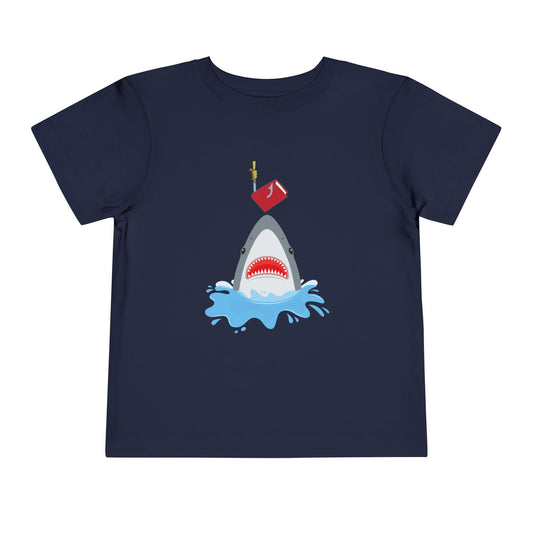 Navy blue toddler t-shirt with a shark graphic jumping out of the water to bite a book on a hook