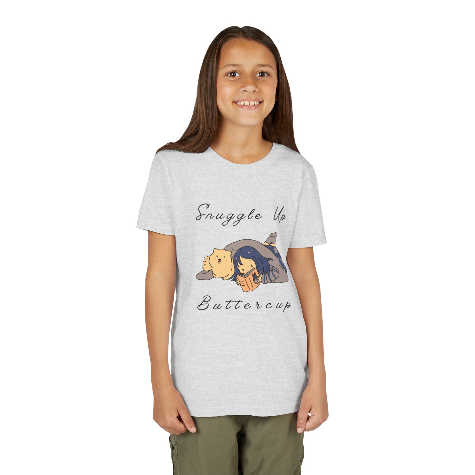 Girl wearing a light gray t-shirt with cartoon design of a girl and her dog reading a book under a blanket and text 'Snuggle Up Buttercup' 