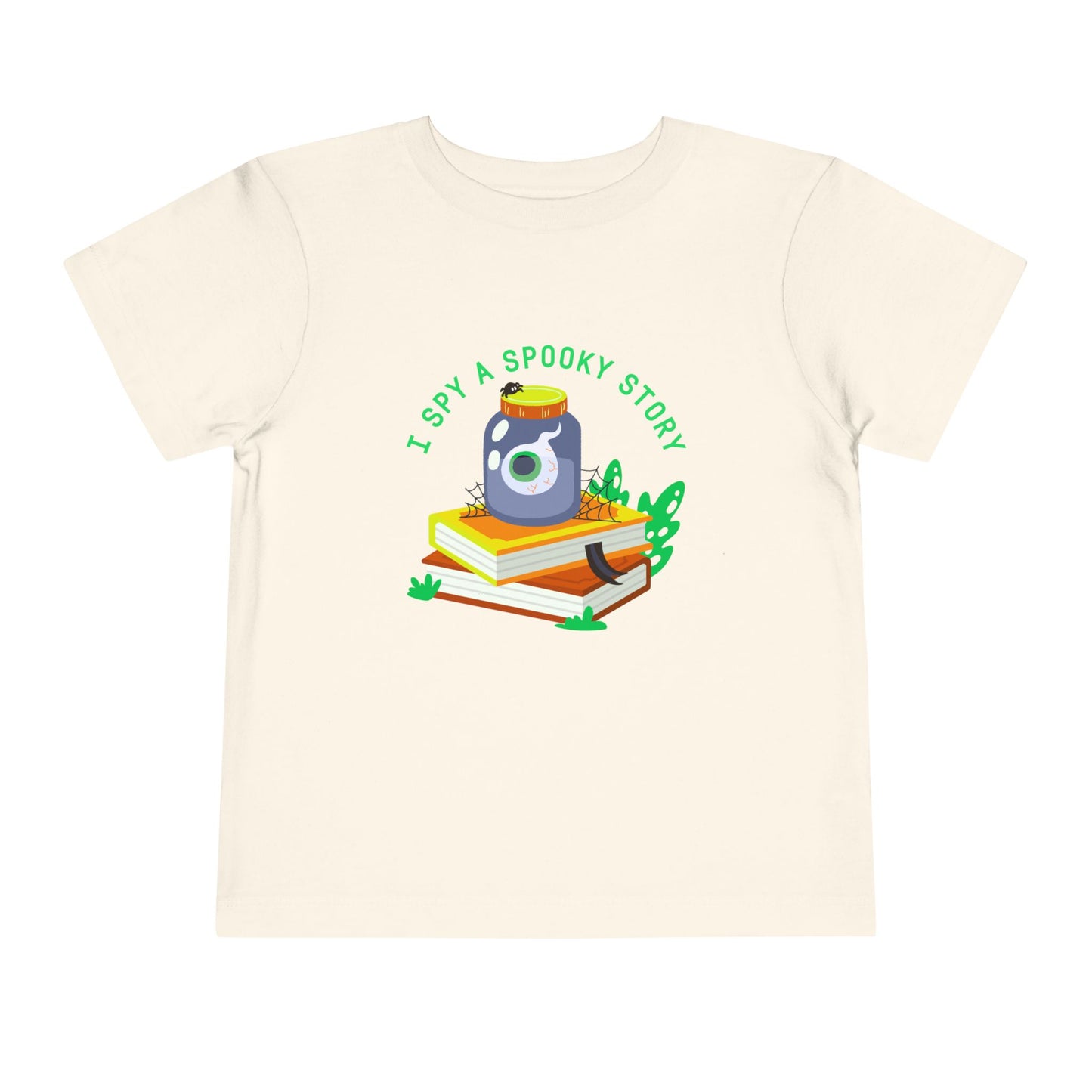 Beige toddler t-shirt with an eyeball in a yar on top of books and text 'I spy a spooky story' on a white background