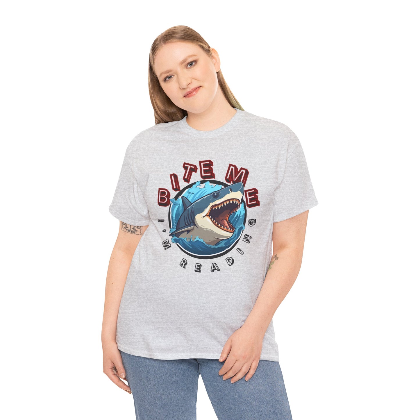 Woman wearing a gray t-shirt with a shark graphic bursting out of the center and text 'Bite Me I'm Reading' 