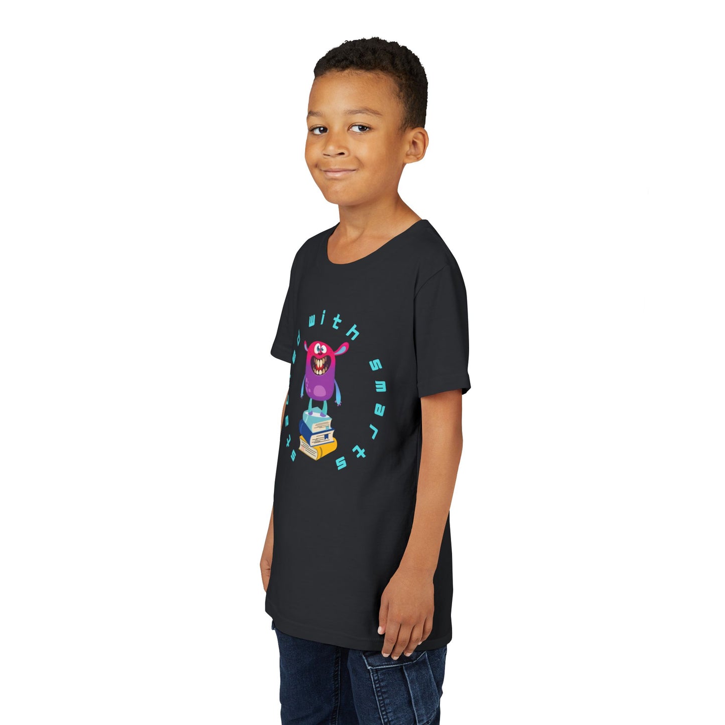 Boy wearing a black t-shirt with a colorful, toothy monster graphic standing on a stack of books, circled by text 'STACKED WITH SMARTS'
