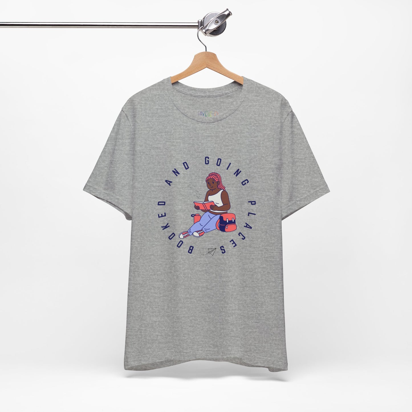 Light gray t-shirt with graphic design of a school girl sitting with a book and text 'Booked And Going Places'