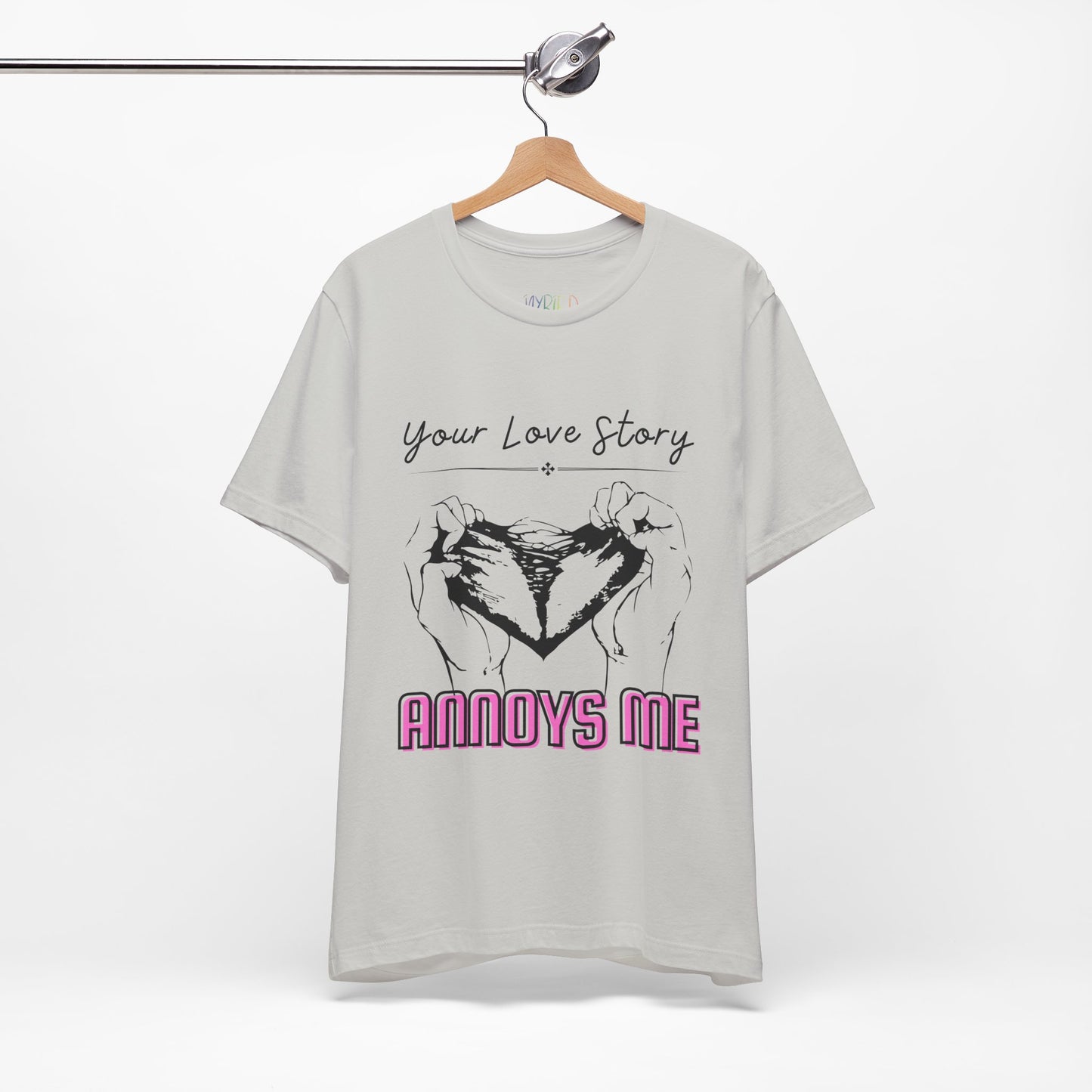 Silver t-shirt with graphic design of two hands pulling apart a heart and text 'Your Love Story ANNOYS ME'