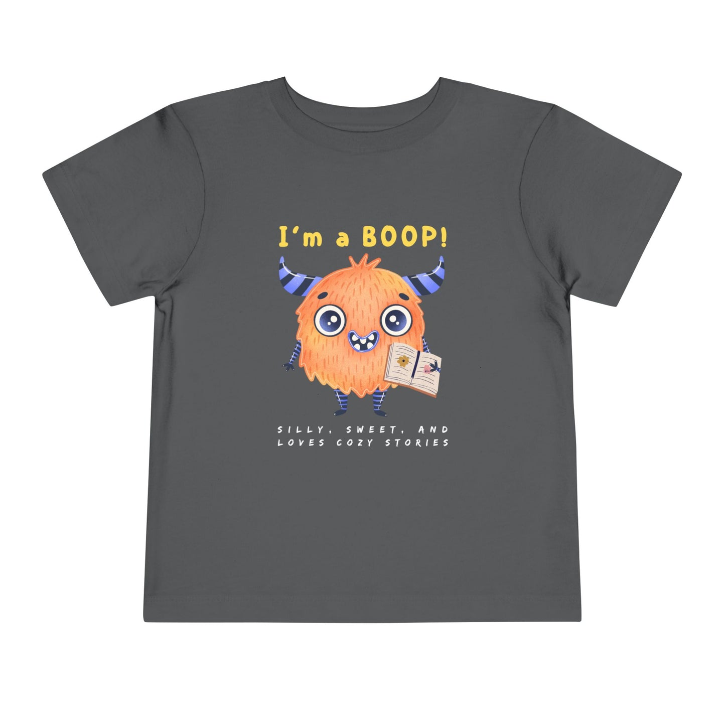 Gray toddler personality t-shirt with a cartoon monster holding a book, proudly proclaiming 'I'm A BOOP!' Sub-text "Silly, Sweet, And Loves Cozy Stories' on a white background