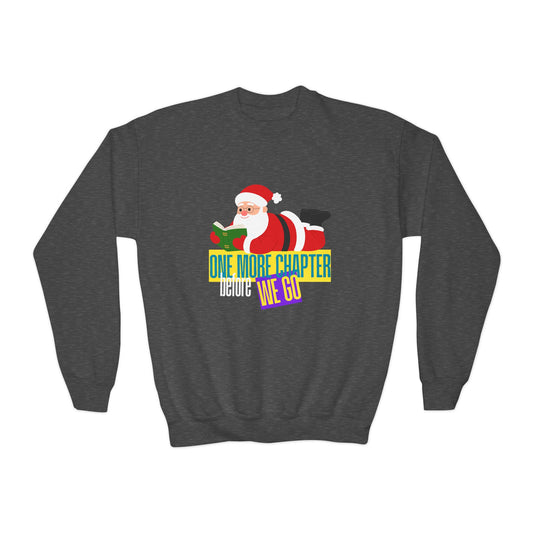 Dark gray sweatshirt with Santa Claus laying on his belly, reading a book and text "One More Chapter Before We Go'