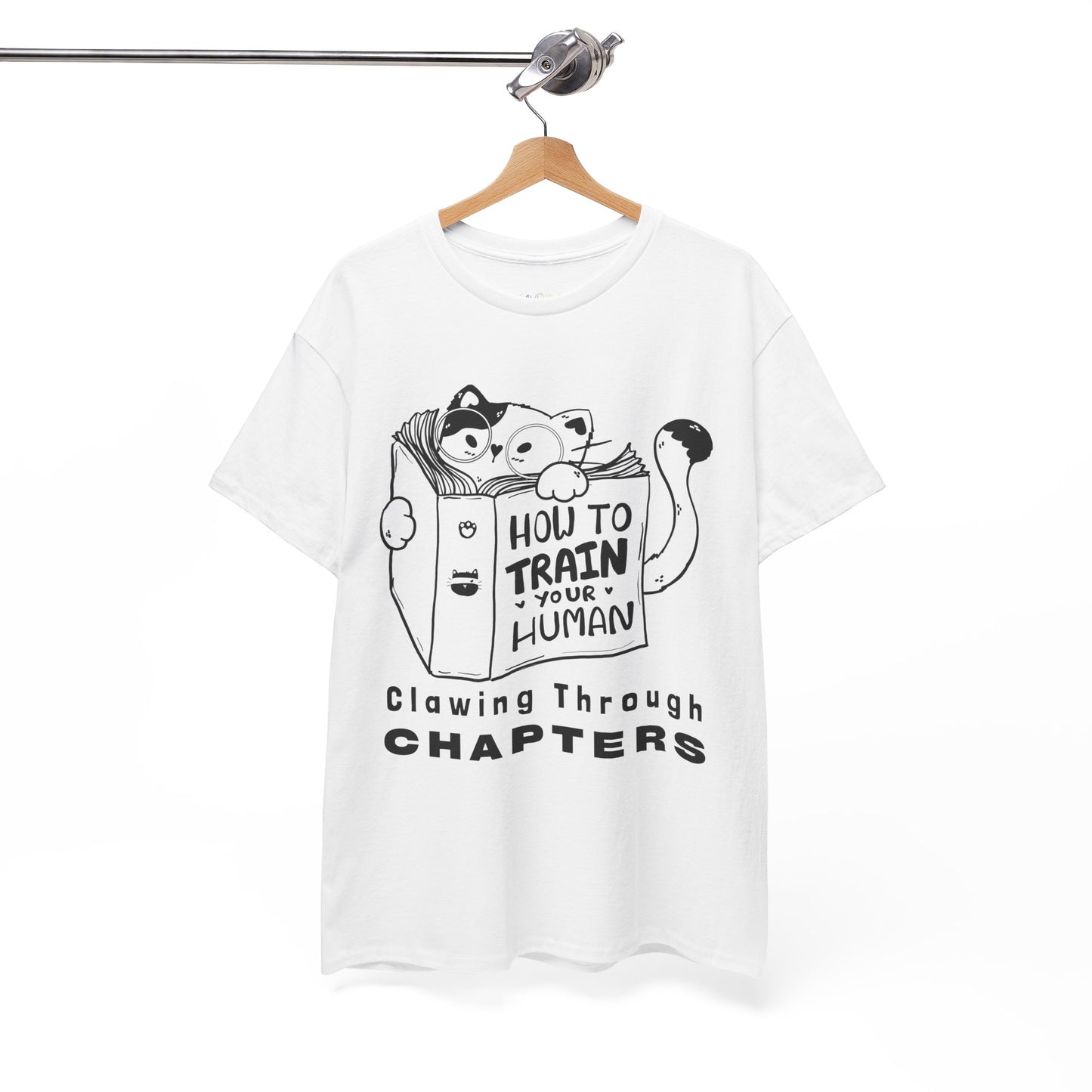White t-shirt with black graphic design of a cat reading a 'How To Train Your Human' book and text 'Clawing Through Chapters'