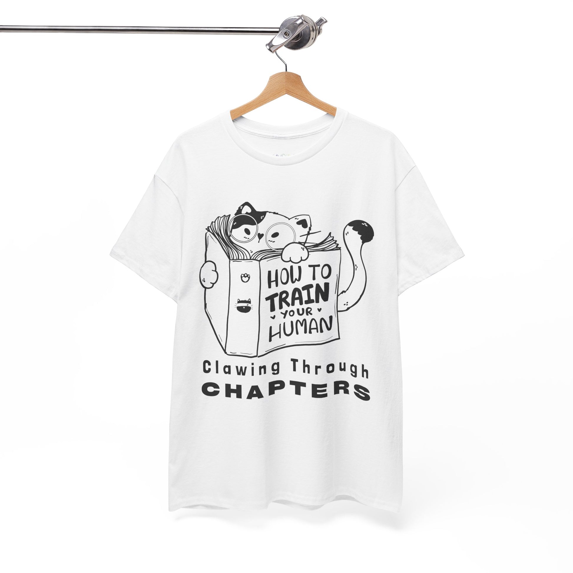 White t-shirt with black graphic design of a cat reading a 'How To Train Your Human' book and text 'Clawing Through Chapters'