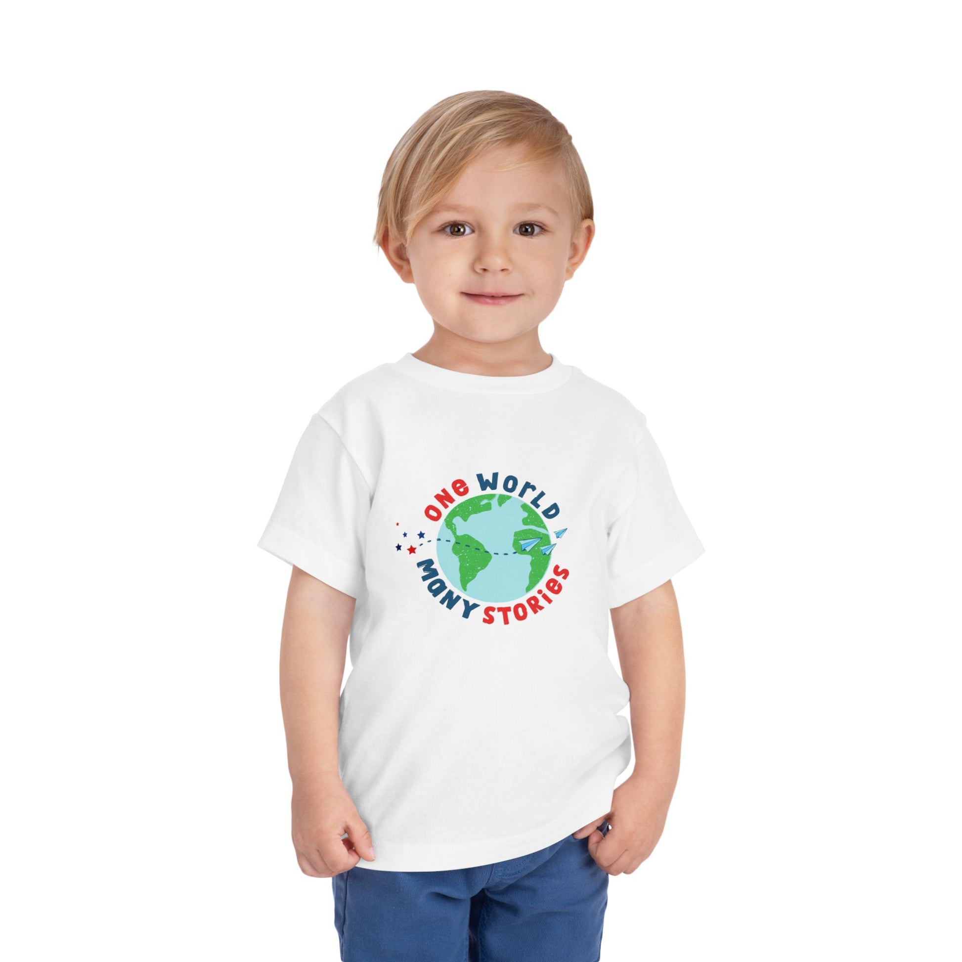 Toddler wearing a white t-shirt with a graphic of the Earth and 'One World, Many Stories' text 