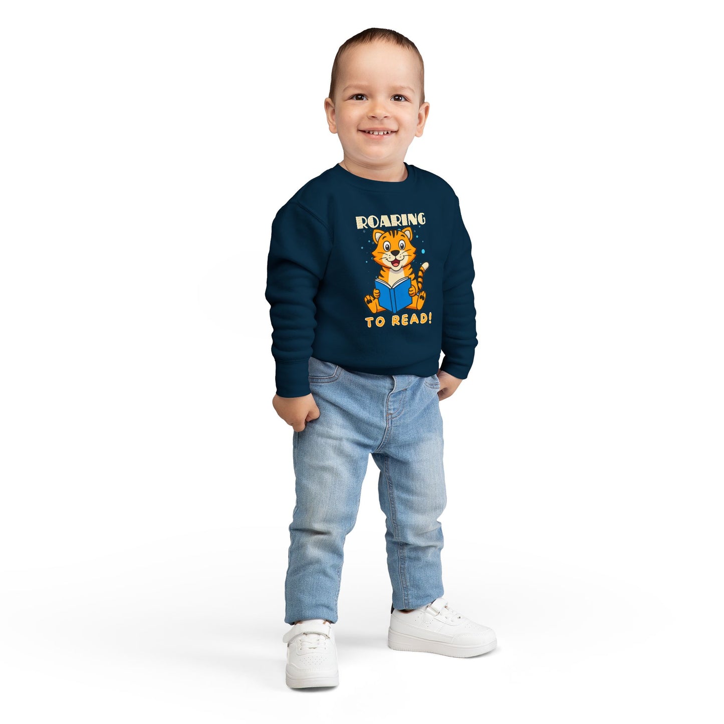 Boy wearing a navy blue toddler sweatshirt with a tiger reading a book graphic and 'Roaring to Read!' text 