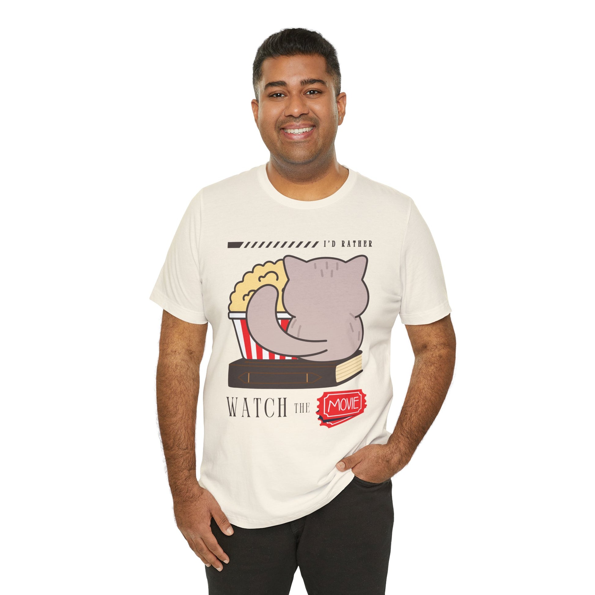 Man wearing a beige t-shirt with the back of a cat, sitting on a book, with a bucket of popcorn, and text 'I'd Rather Watch The Movie' 
