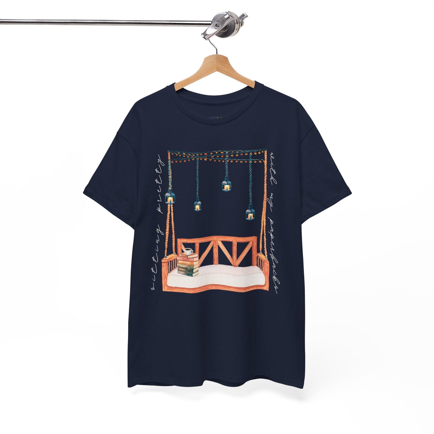 Navy blue t-shirt with a porch swing, string lights, hot beverage and a stack of books, text says 'Sitting Pretty With My Paperbacks'