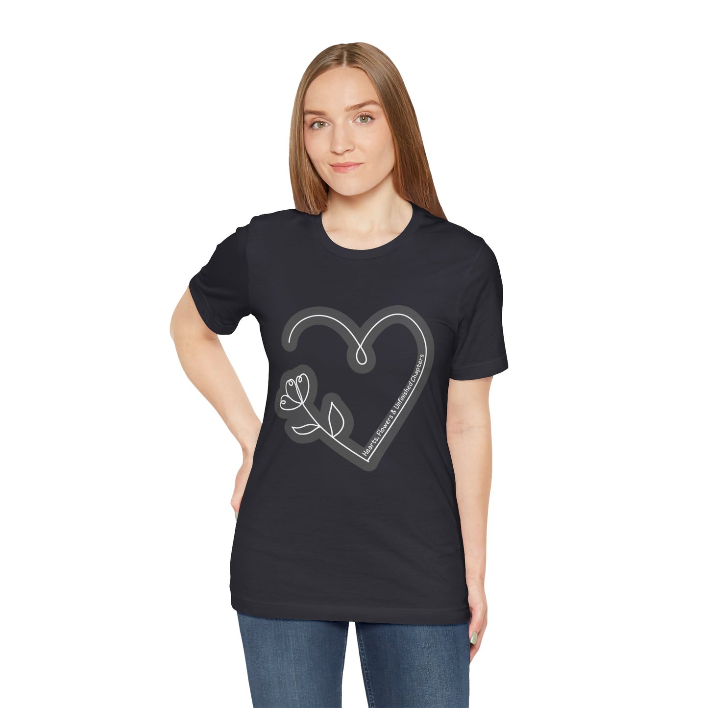 Woman wearing a dark grey t-shirt with a gray heart and flower sketched design and text 'Hearts, Flowers & Unfinished Chapters'