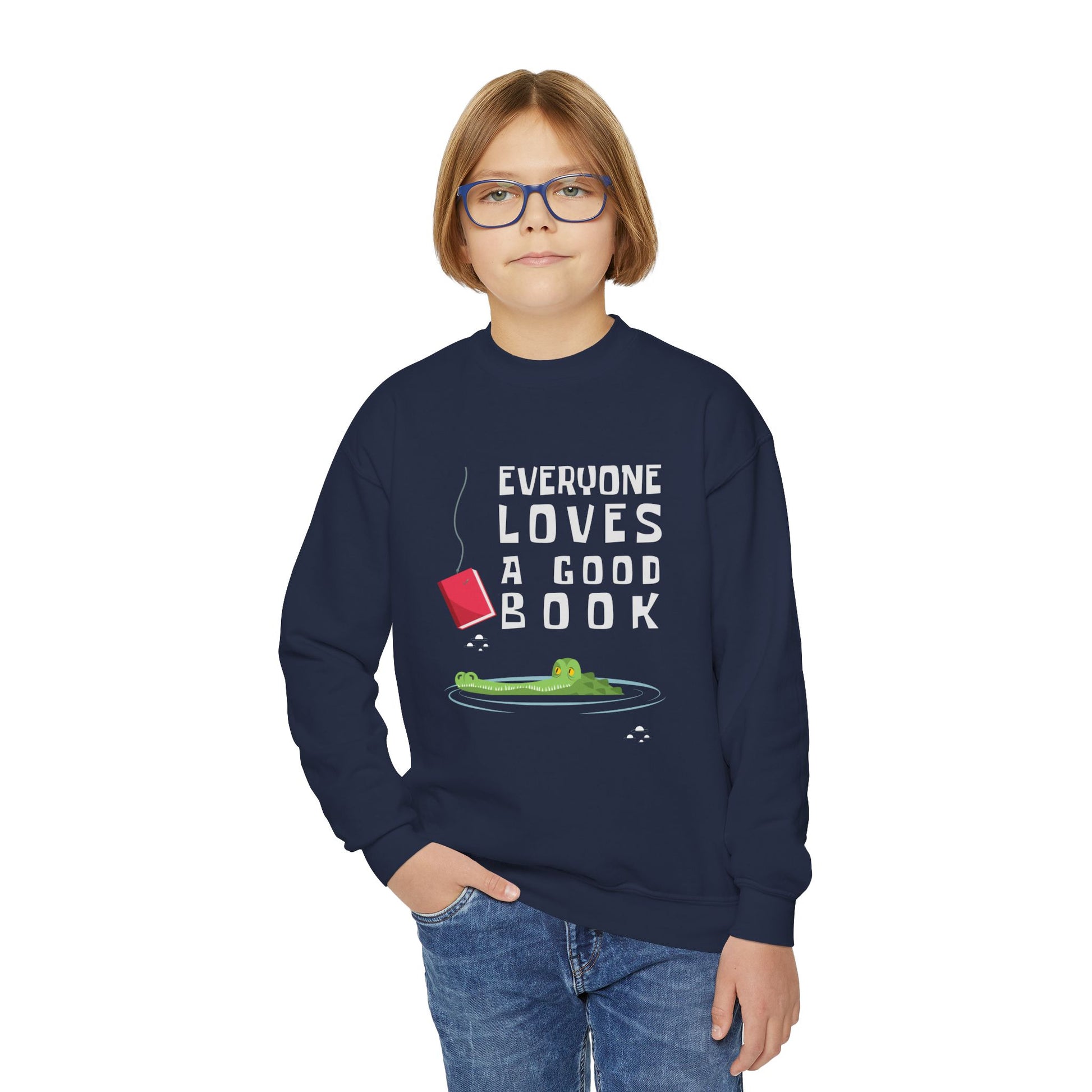 Boy wearing a navy blue sweatshirt with a of an alligator looking at a book on a hook and text 'everyone loves a good book'
