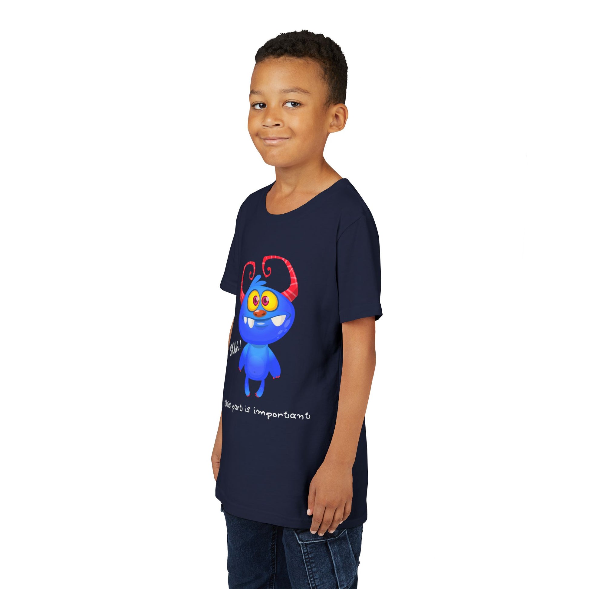 Boy wearing a navy blue t-shirt with a wide-eyed, gap toothed, blue cartoon monster and text 'Shhh! This part is important.'