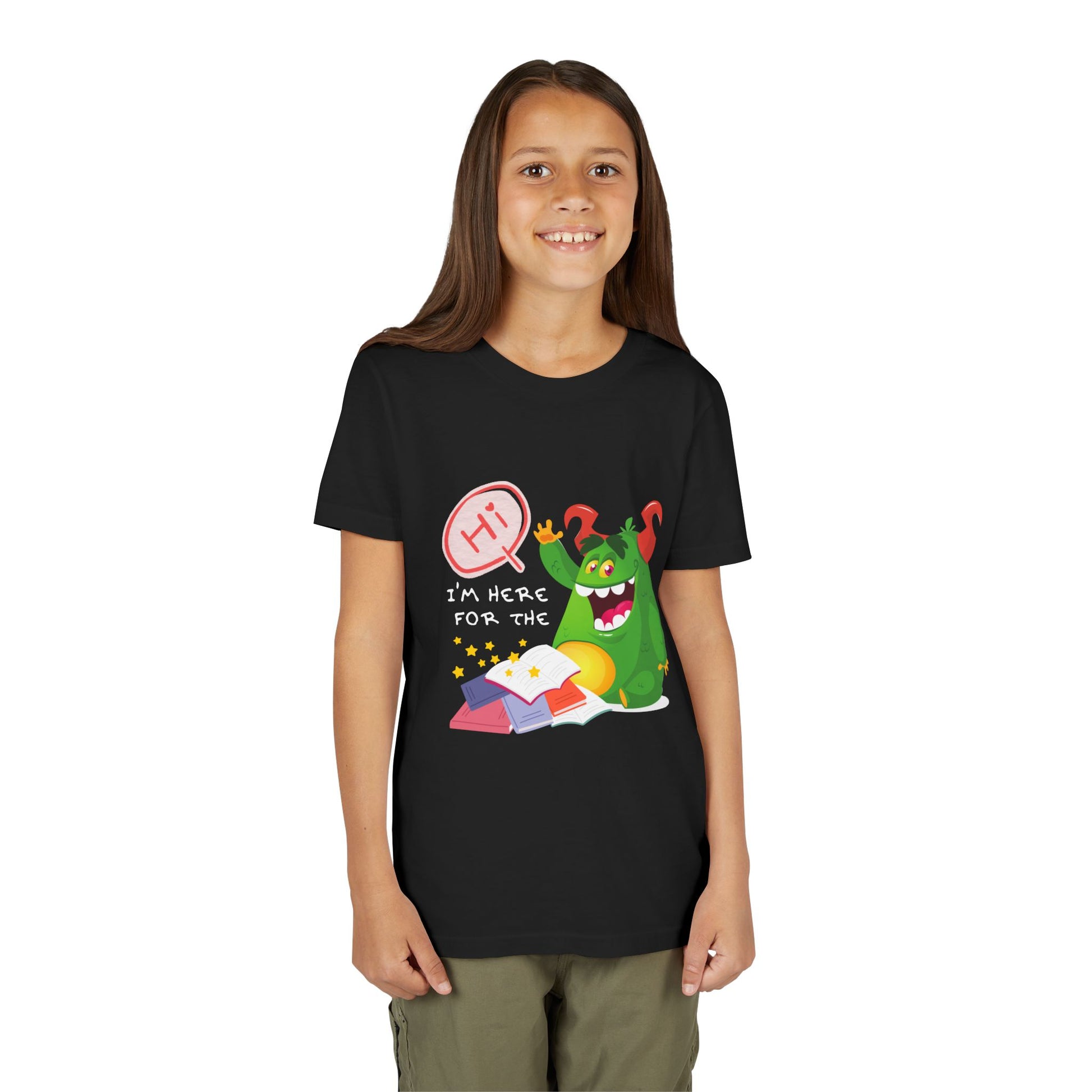 Girl wearing a black t-shirt with a chubby green monster waiving, with text 'Hi, I'm Here For The' above a messy stack of books