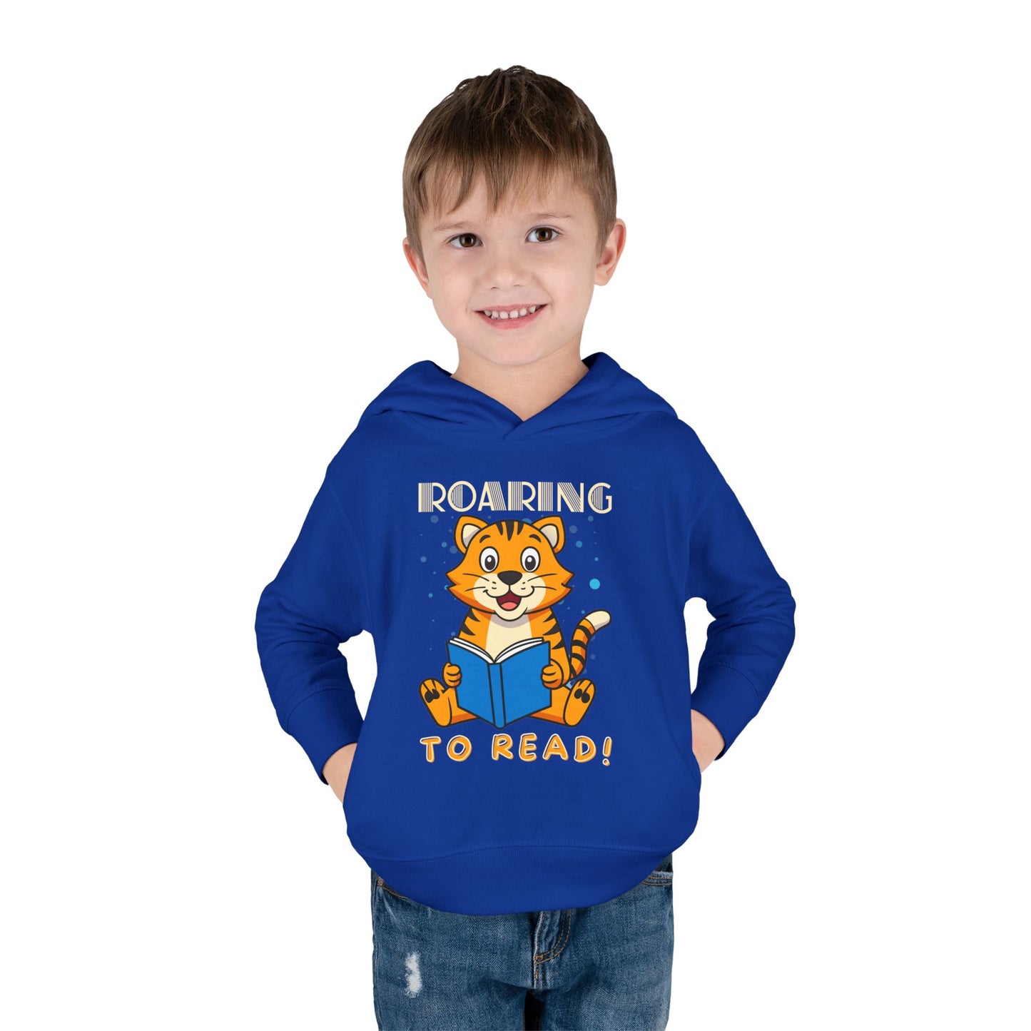 Boy wearing a blue toddler hoodie with a tiger reading a book and text 'ROARING TO READ!'