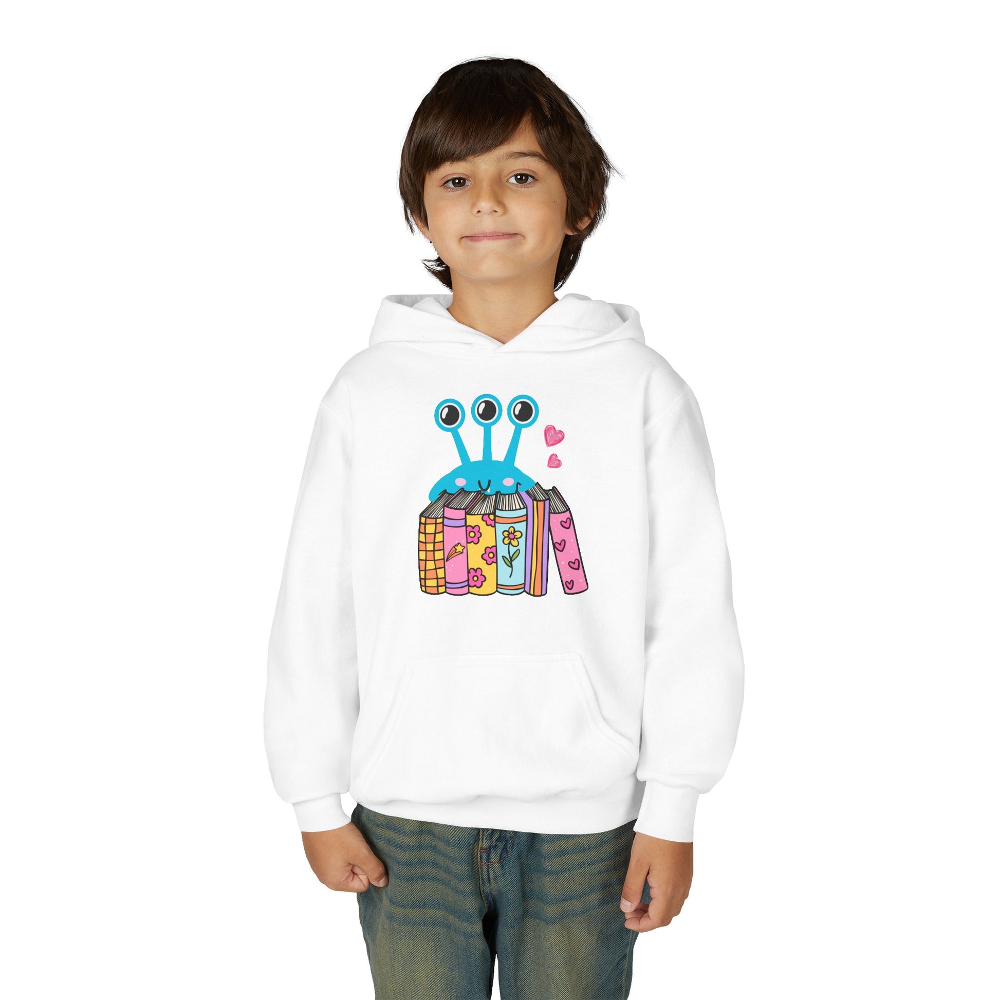 Boy wearing a white hoodie with a three eyed alien standing behind a row of books