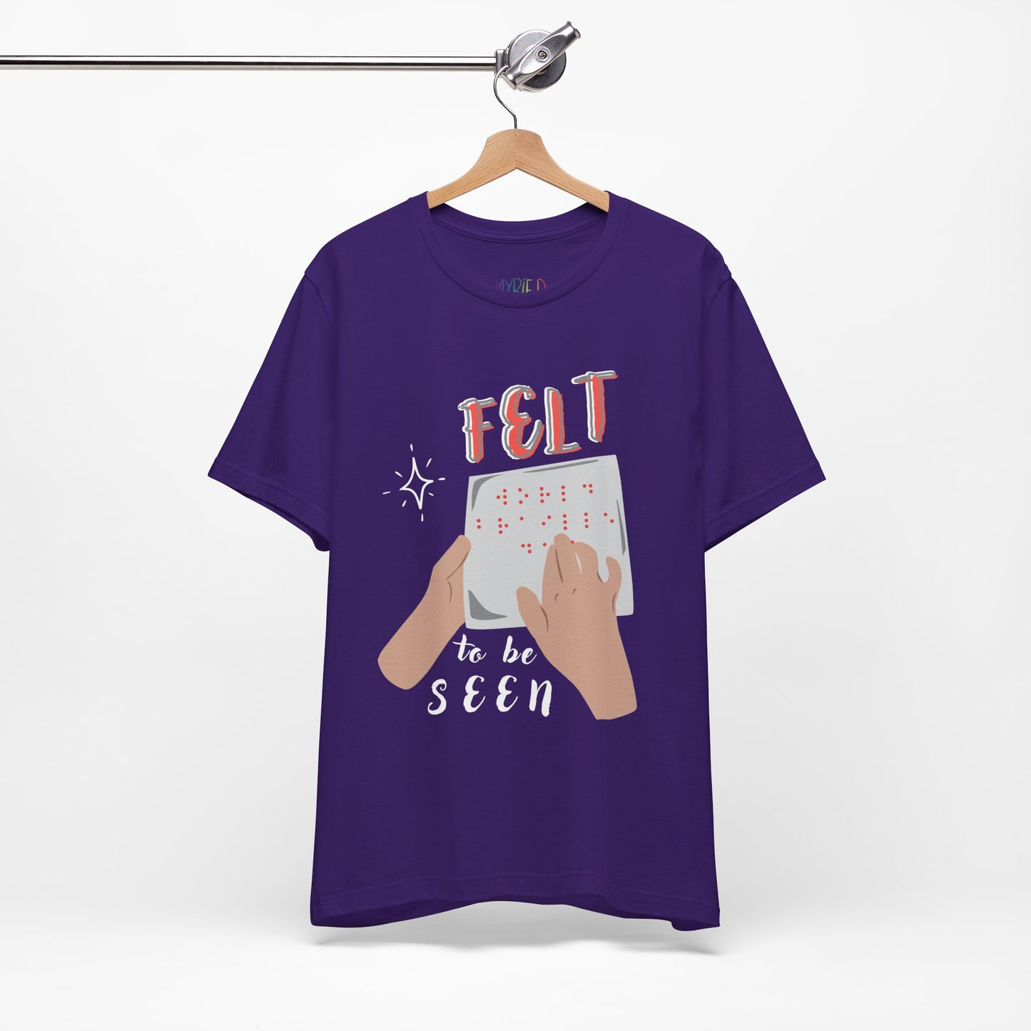 Purple t-shirt with graphic design of hands reading braille text and 'Felt To Be Seen' messaging 