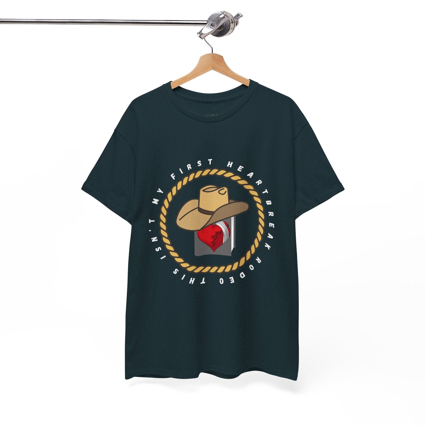 Dark t-shirt with a cowboy hat atop a book with a broken heart, circled by a rope and text 'This Isn't My First Heartbreak Rodeo'
