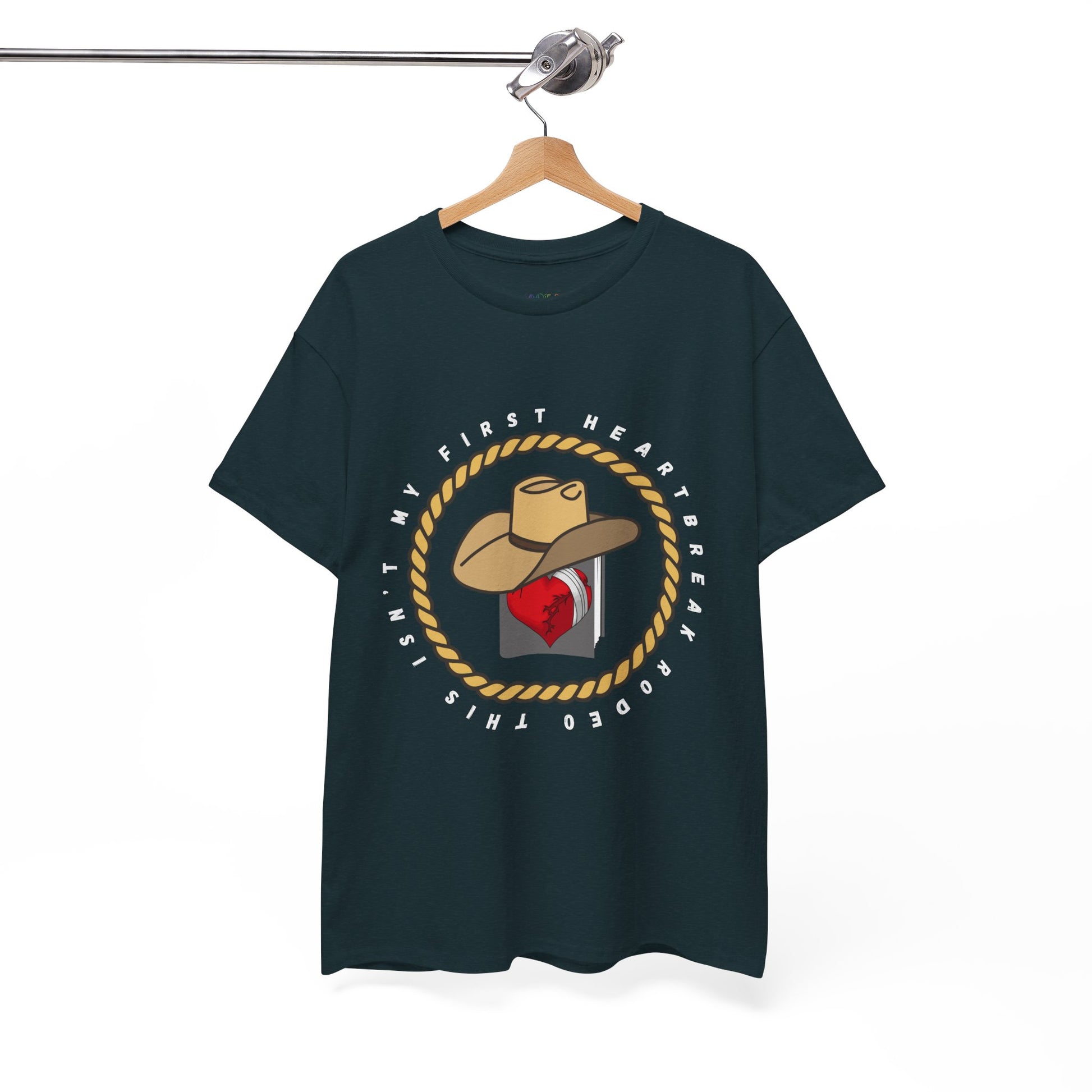 Dark t-shirt with a cowboy hat atop a book with a broken heart, circled by a rope and text 'This Isn't My First Heartbreak Rodeo'