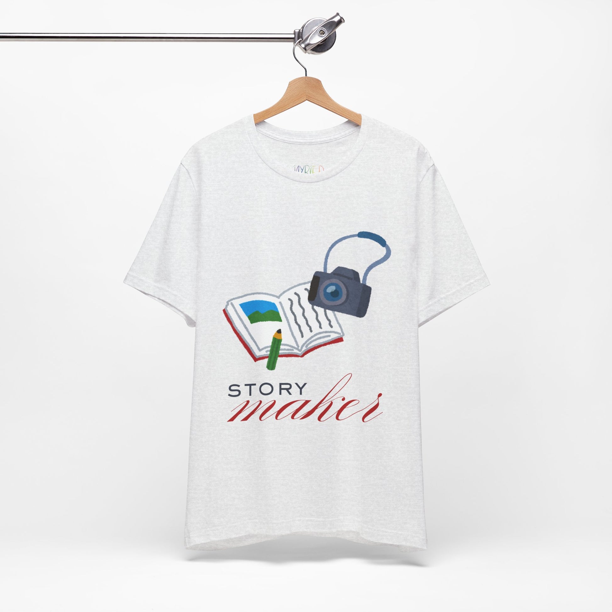 Light ash gray t-shirt with an open book, pencil and camera, 'Story Maker' text beneath