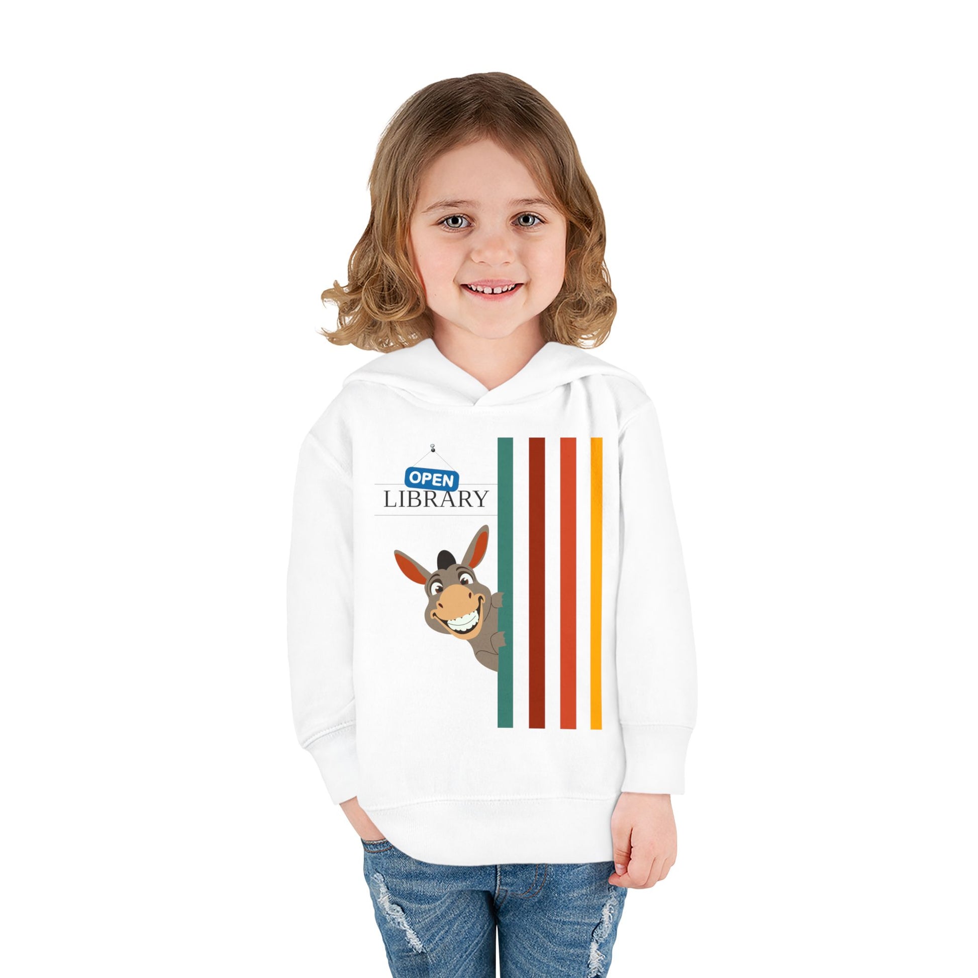 Girl wearing a white toddler hoodie with a cartoon donkey peaking around a wall of rainbow strips and 'Open Library' signage