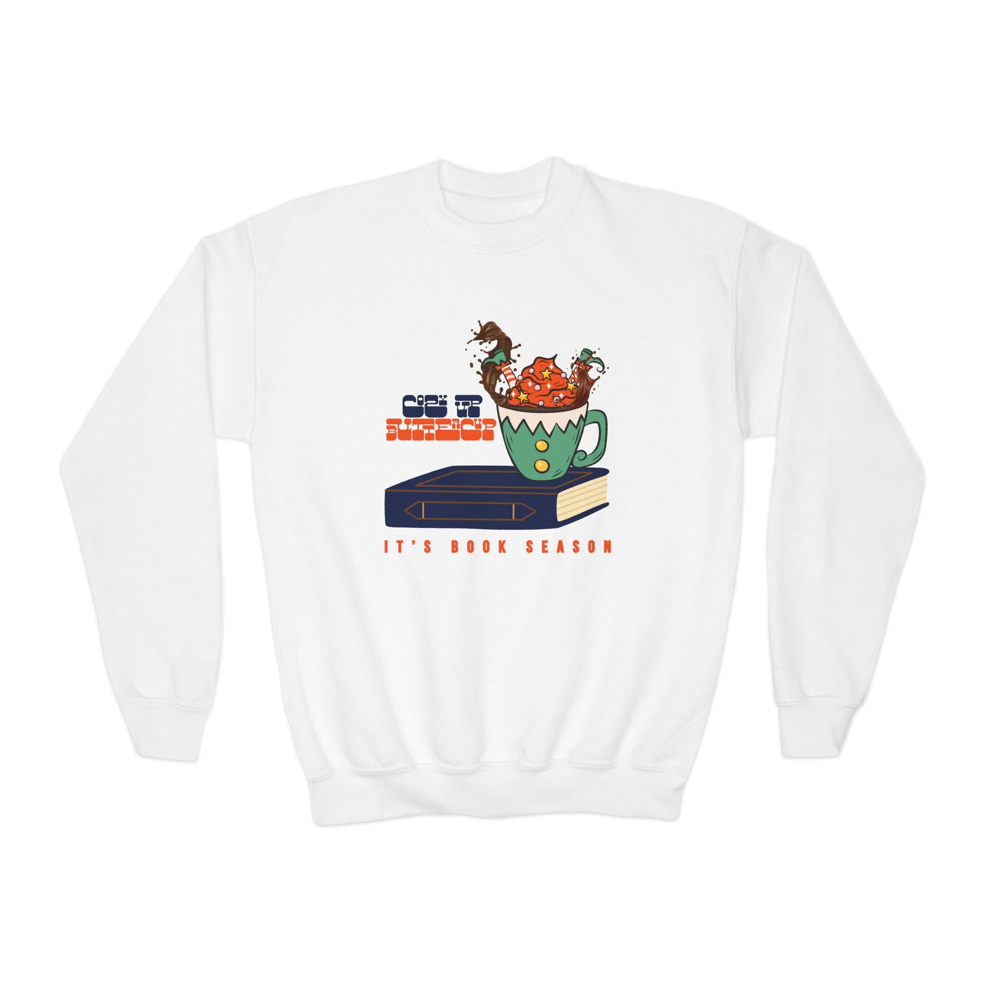 White sweatshirt with an elf splashing upside down in a mug of hot chocolate on a book, text 'Cozy Up Buttercup, It's Book Season'