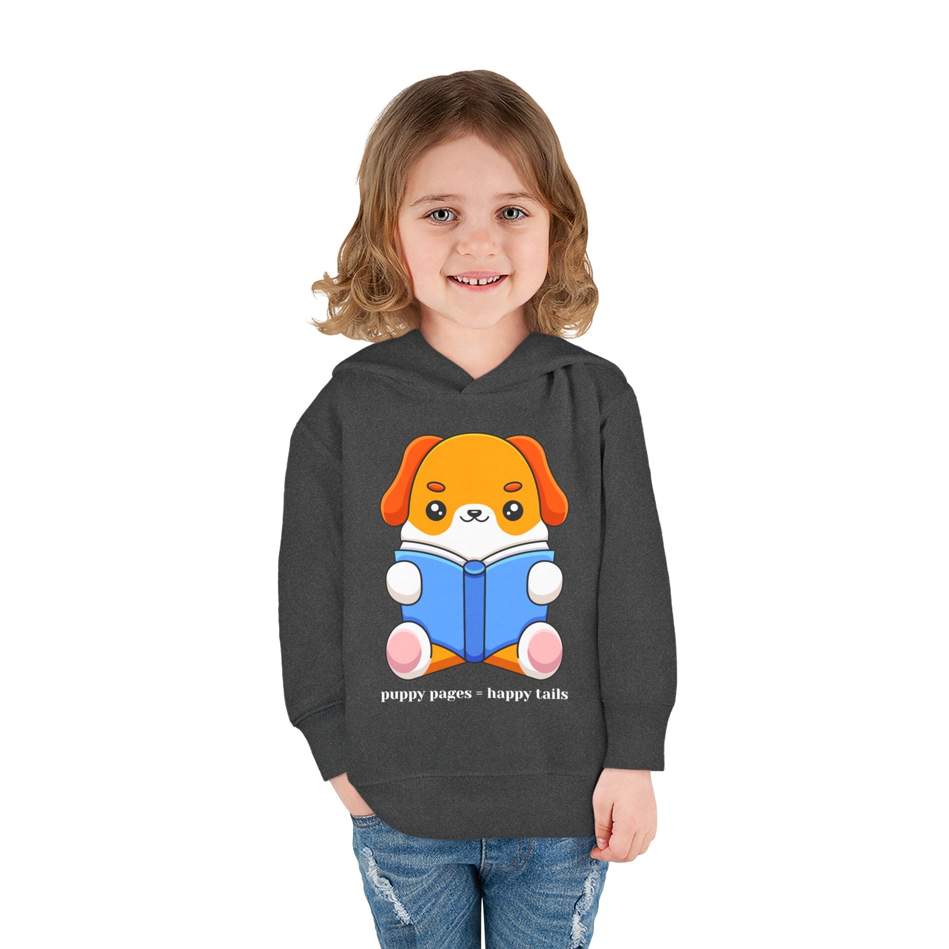 Girl wearing a dark gray toddler hoodie with a cartoon dog reading a book and text 'puppy pages - happy tails'
