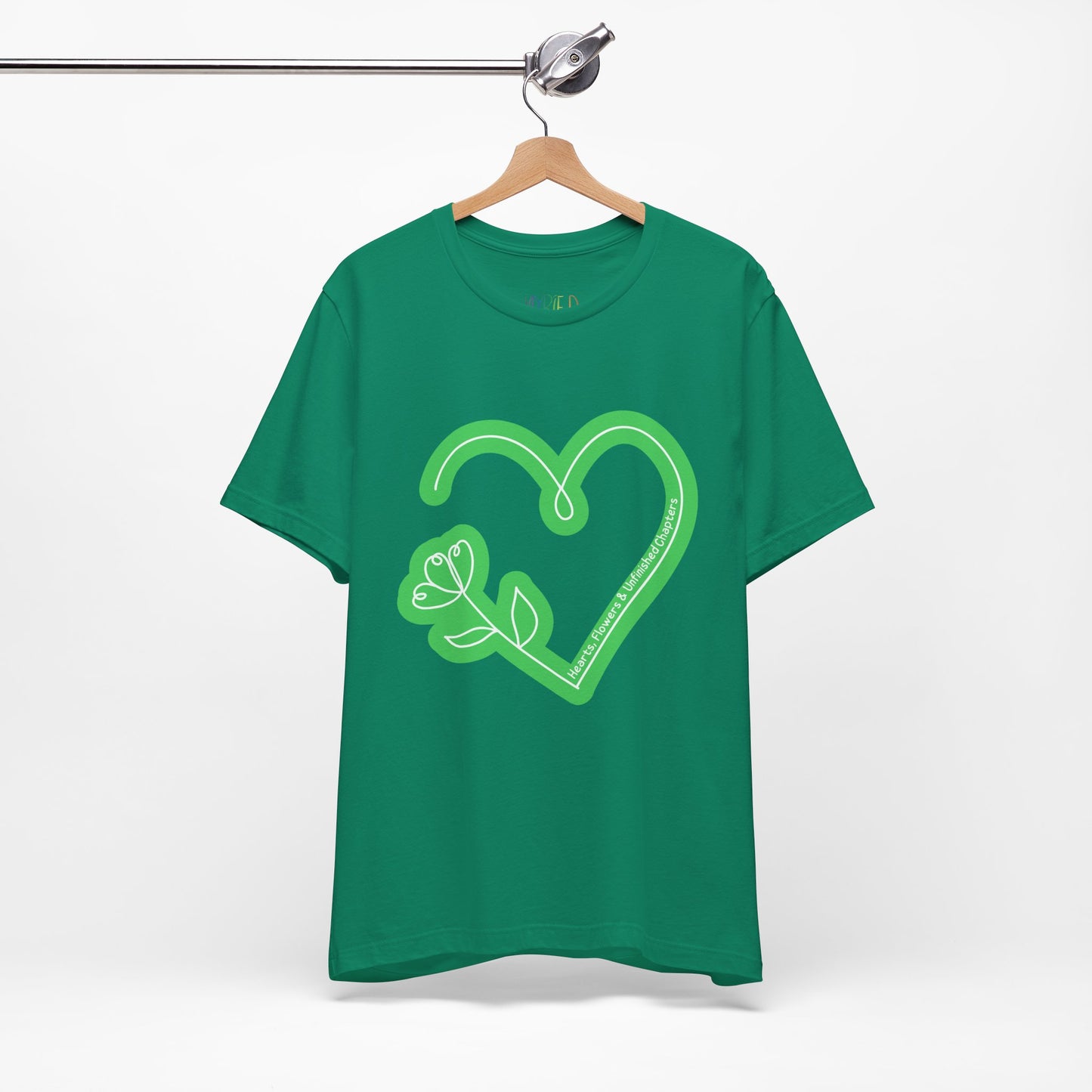 Green t-shirt with a light green heart and flower sketched design and text 'Hearts, Flowers & Unfinished Chapters'