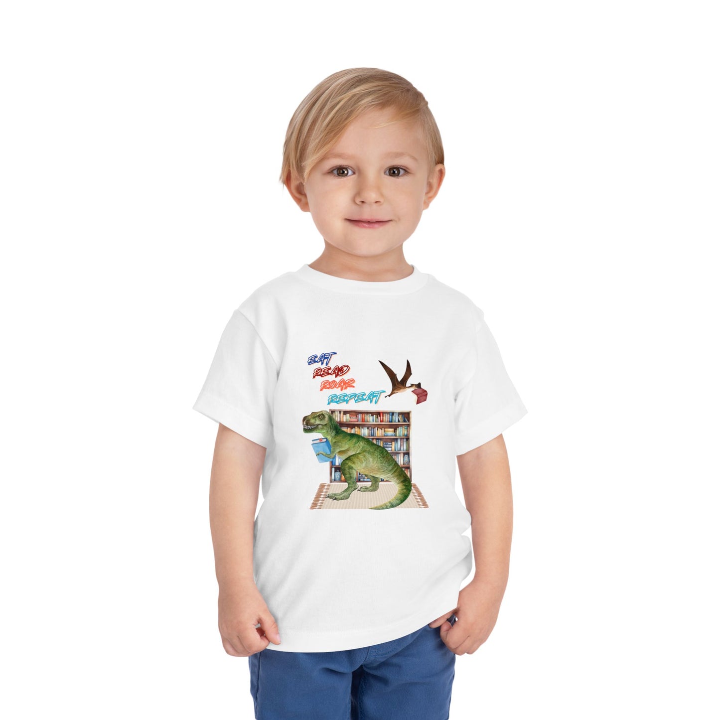 Child wearing a white toddler t-shirt with a t-rex dinosaur checking out a book at the library, a tera dactyl flying overhead with a book and text 'Eat, Read, Roar, Repeat' 