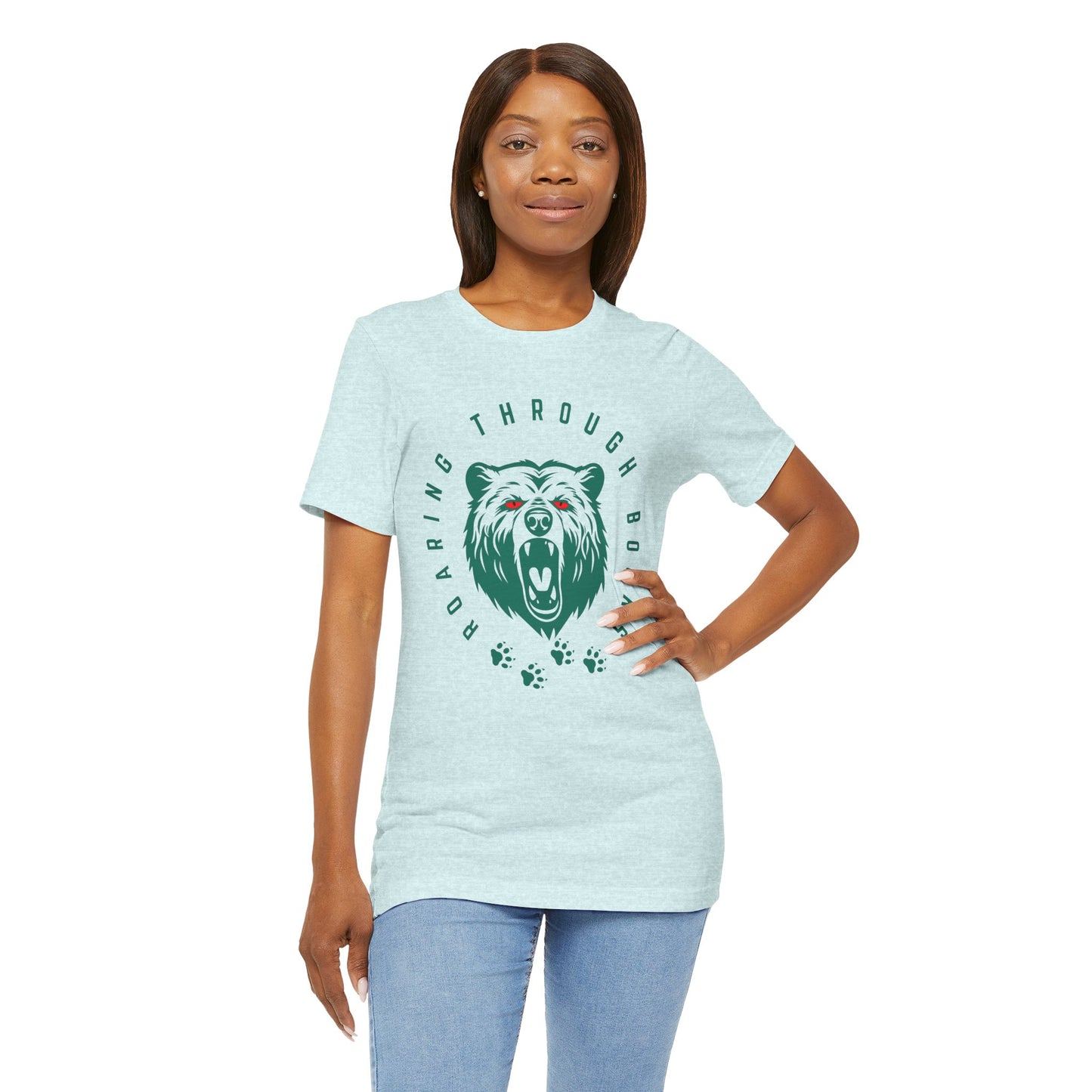 Woman wearing a light ice blue t-shirt with a green bear graphic, red eyes and circular text 'Roaring Through Books'