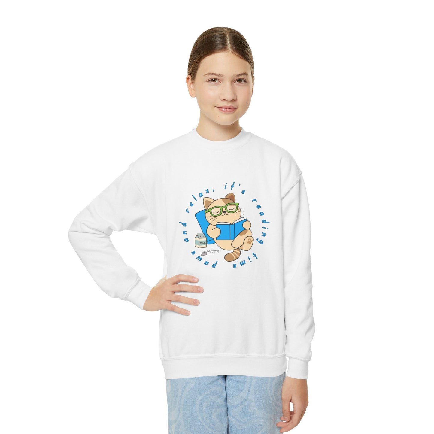 Girl wearing a white sweatshirt with a cartoon cat reading a book, circled by text 'paws and relax, it's reading time'